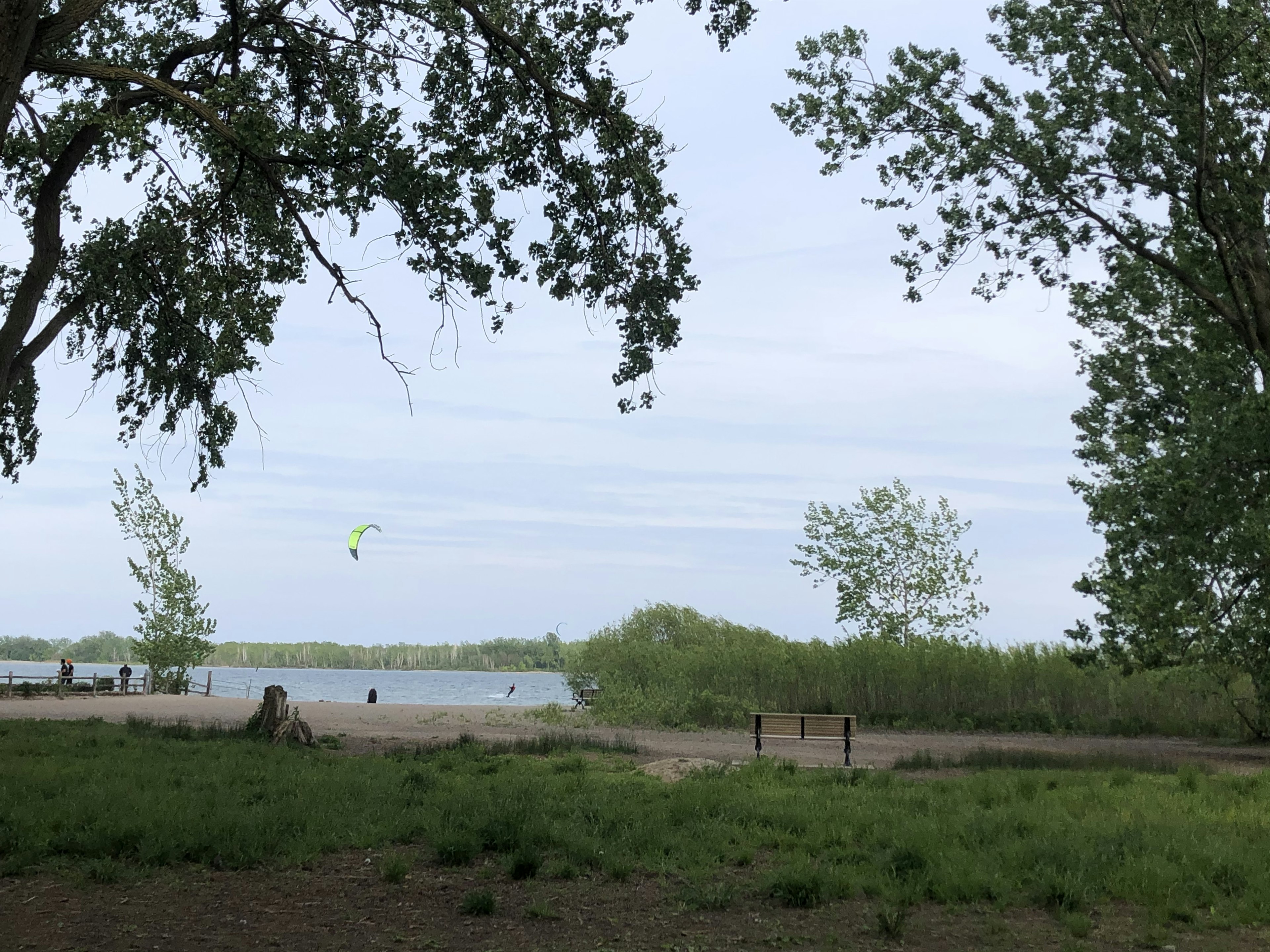 Malersicher Blick auf einen See umgeben von üppigem Grün mit sichtbarem Gleitschirm