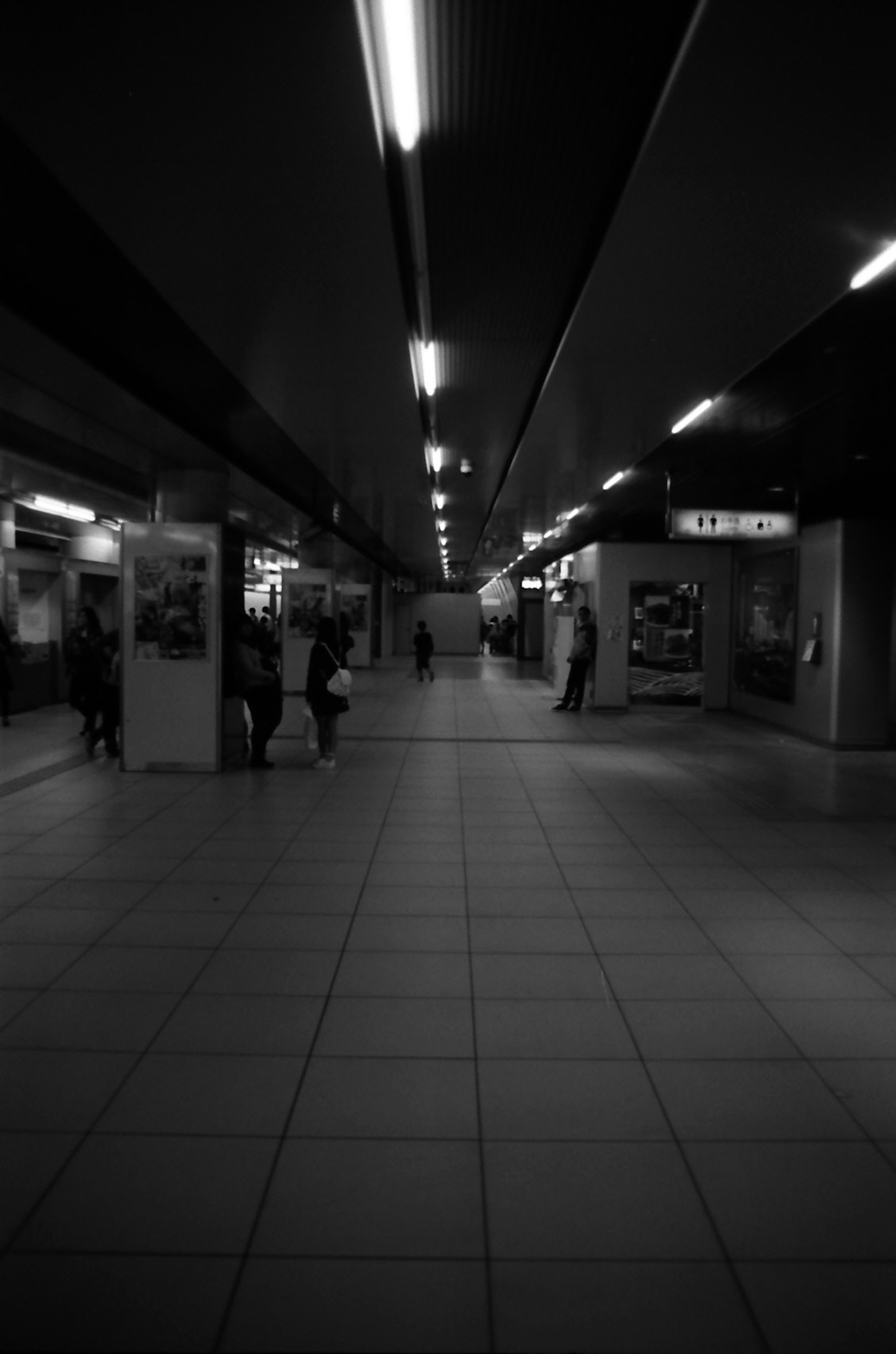 黒と白の地下鉄駅の通路 人々が歩いている 照明が特徴的