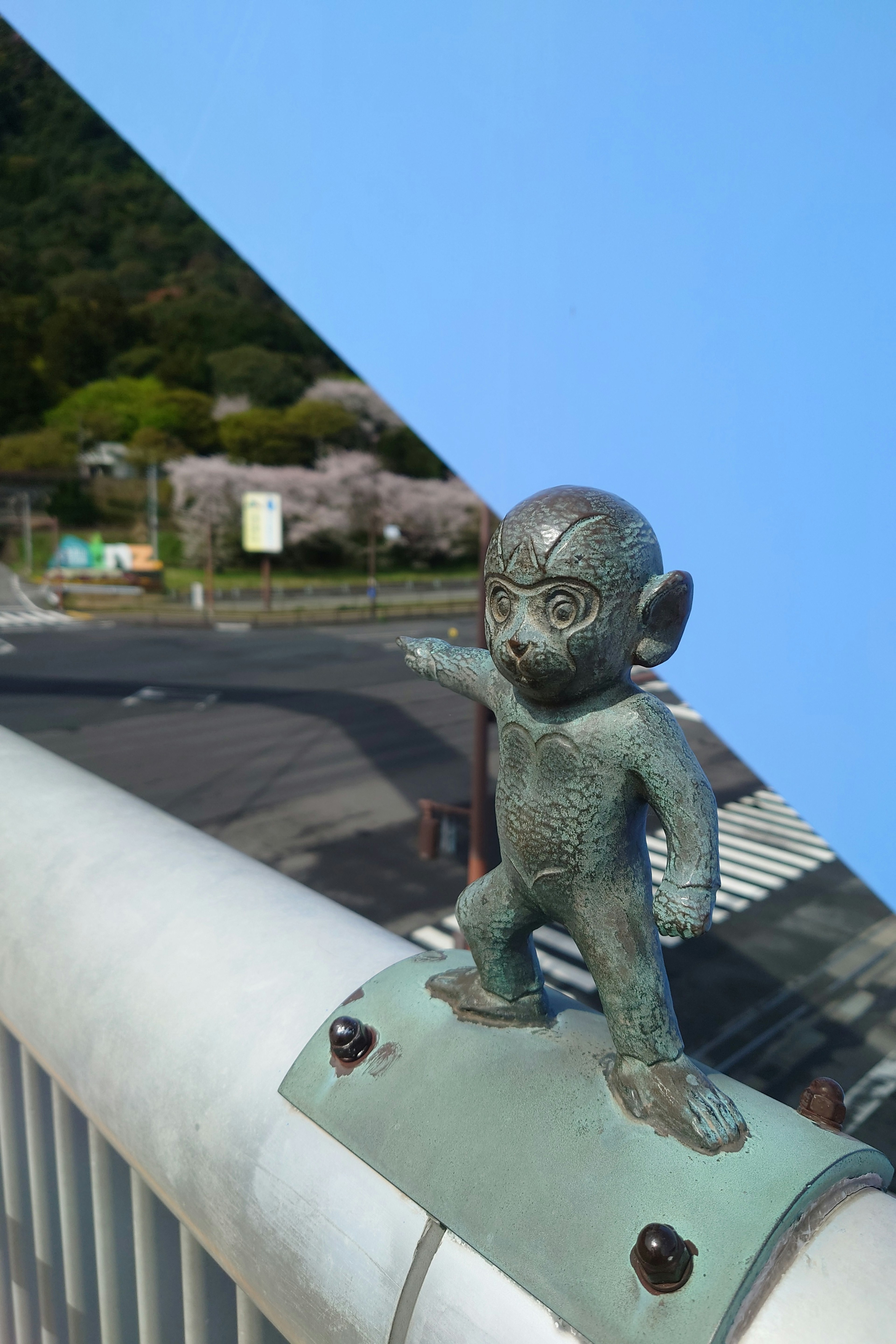 Una estatua de mono en la barandilla de un puente señalando hacia adelante