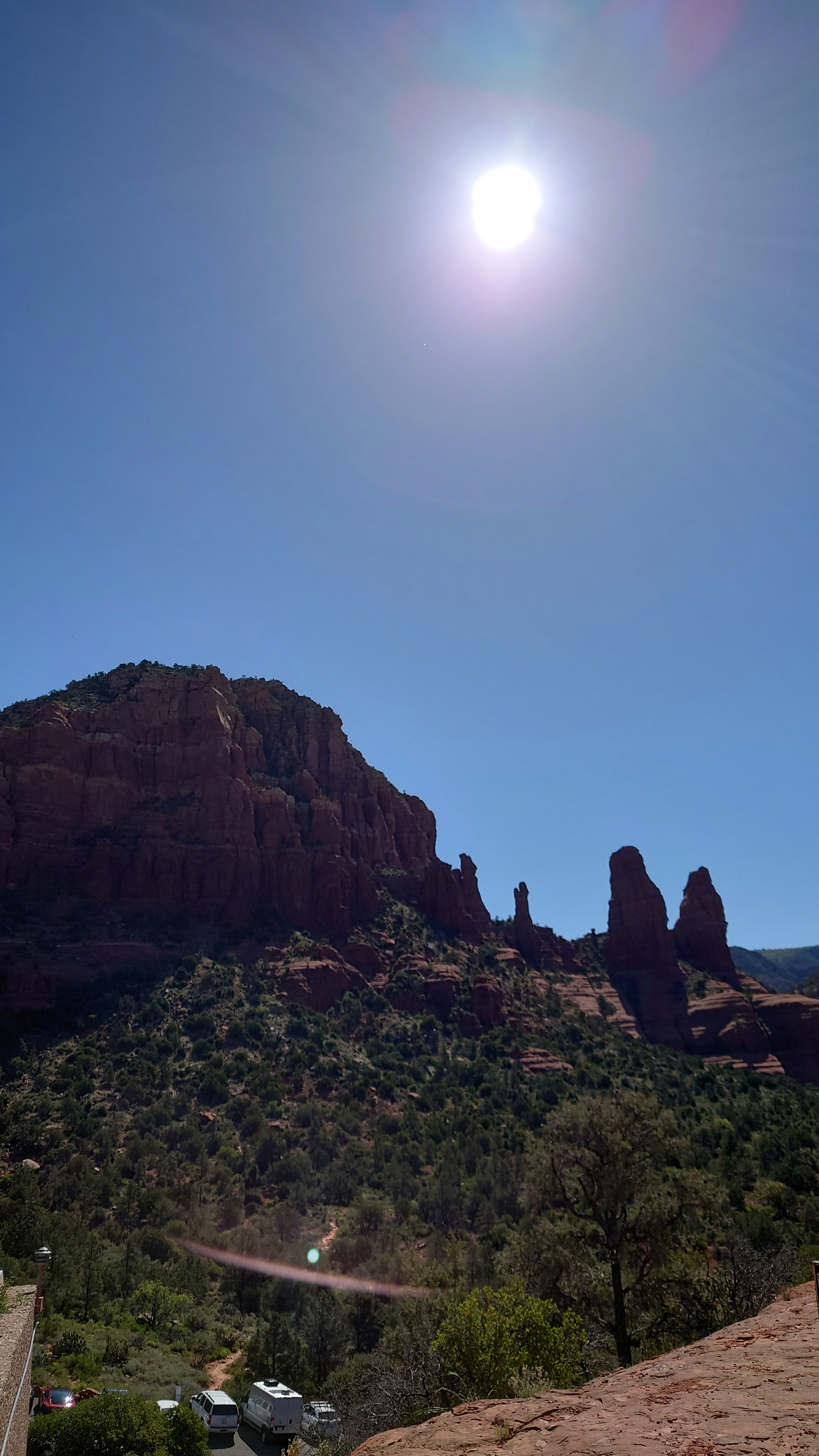 Red rock formations under a bright sky with the sun