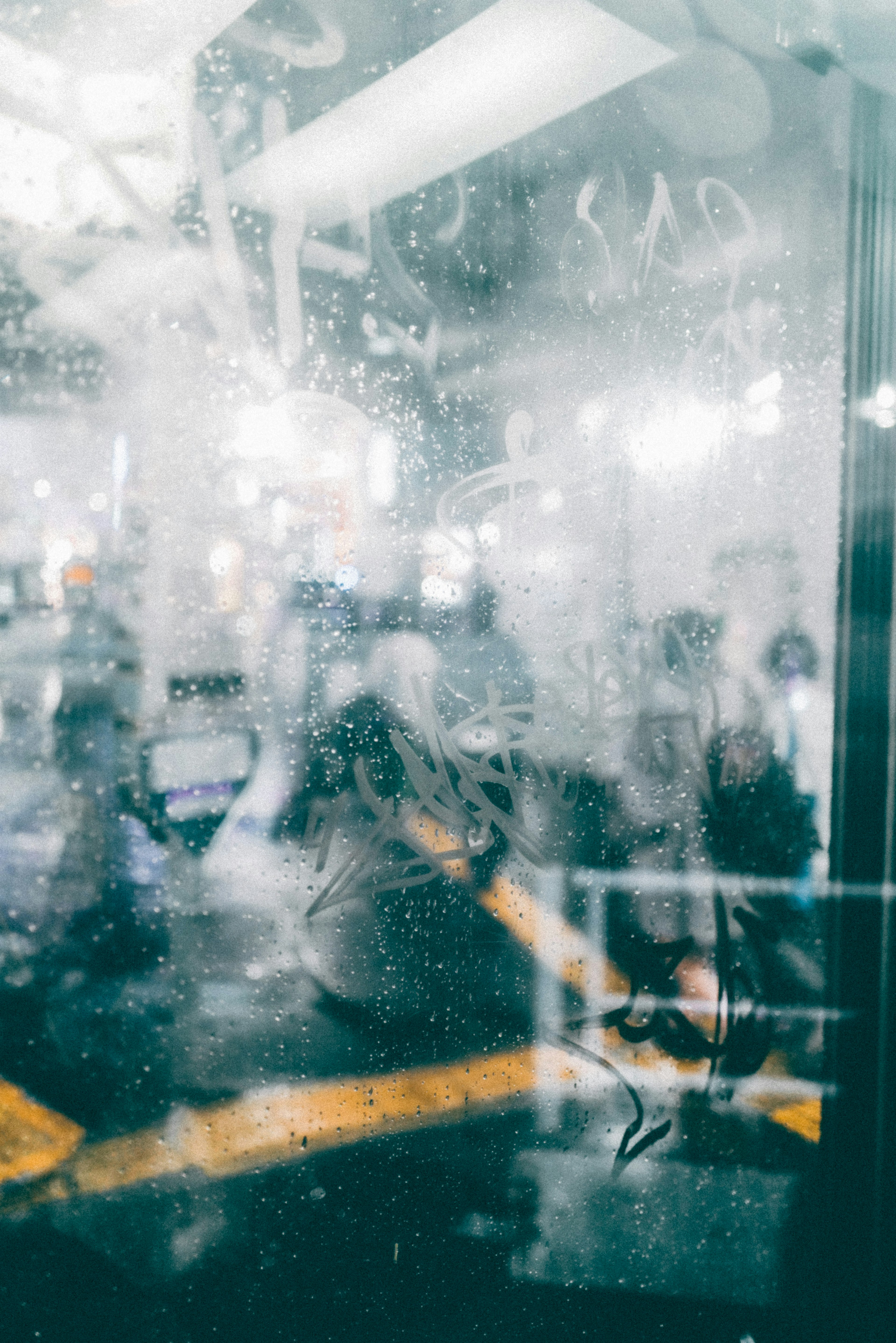 People and blurred background visible through a glass with water droplets