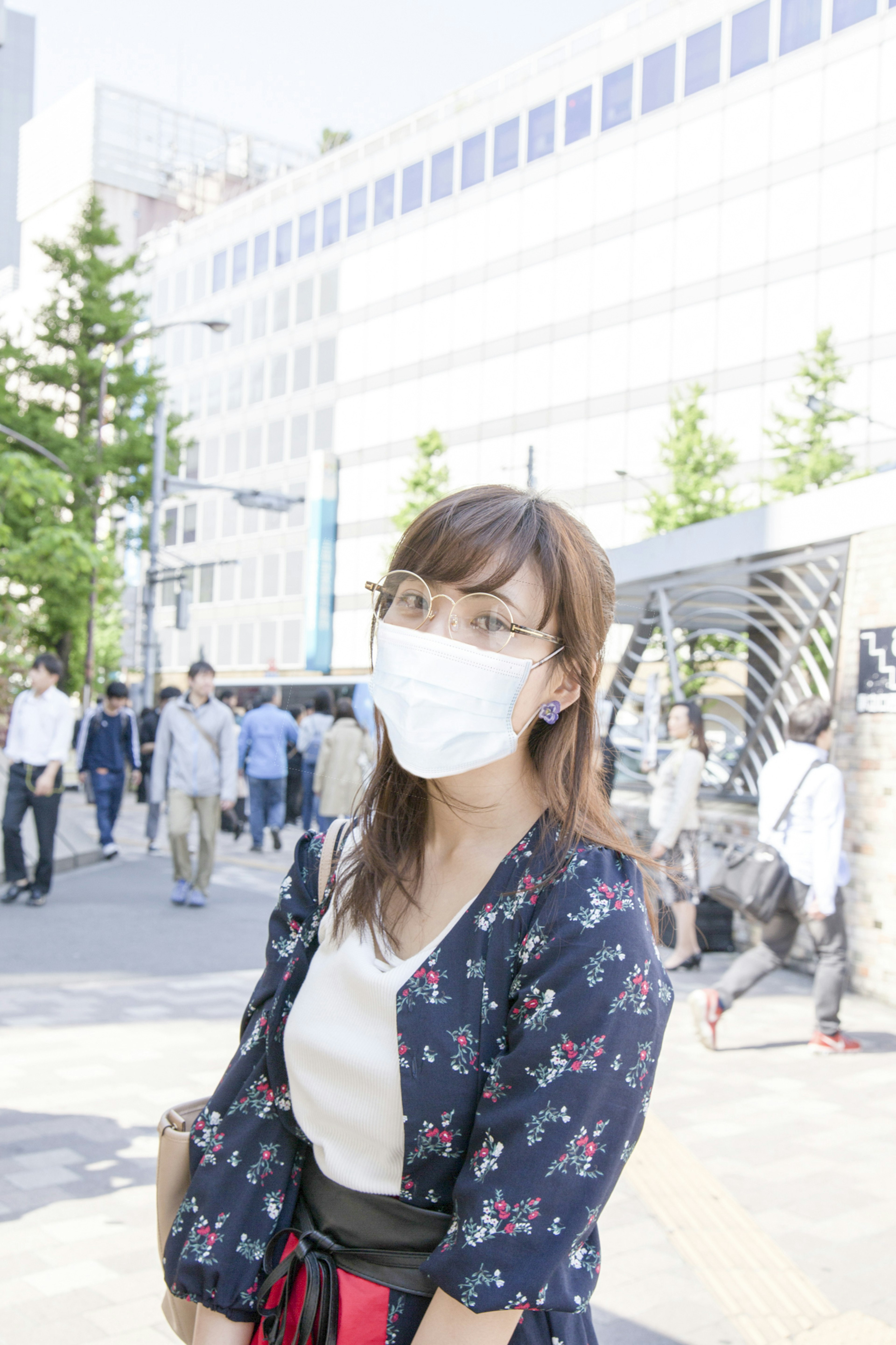 Woman wearing a mask and floral clothing in a city street scene