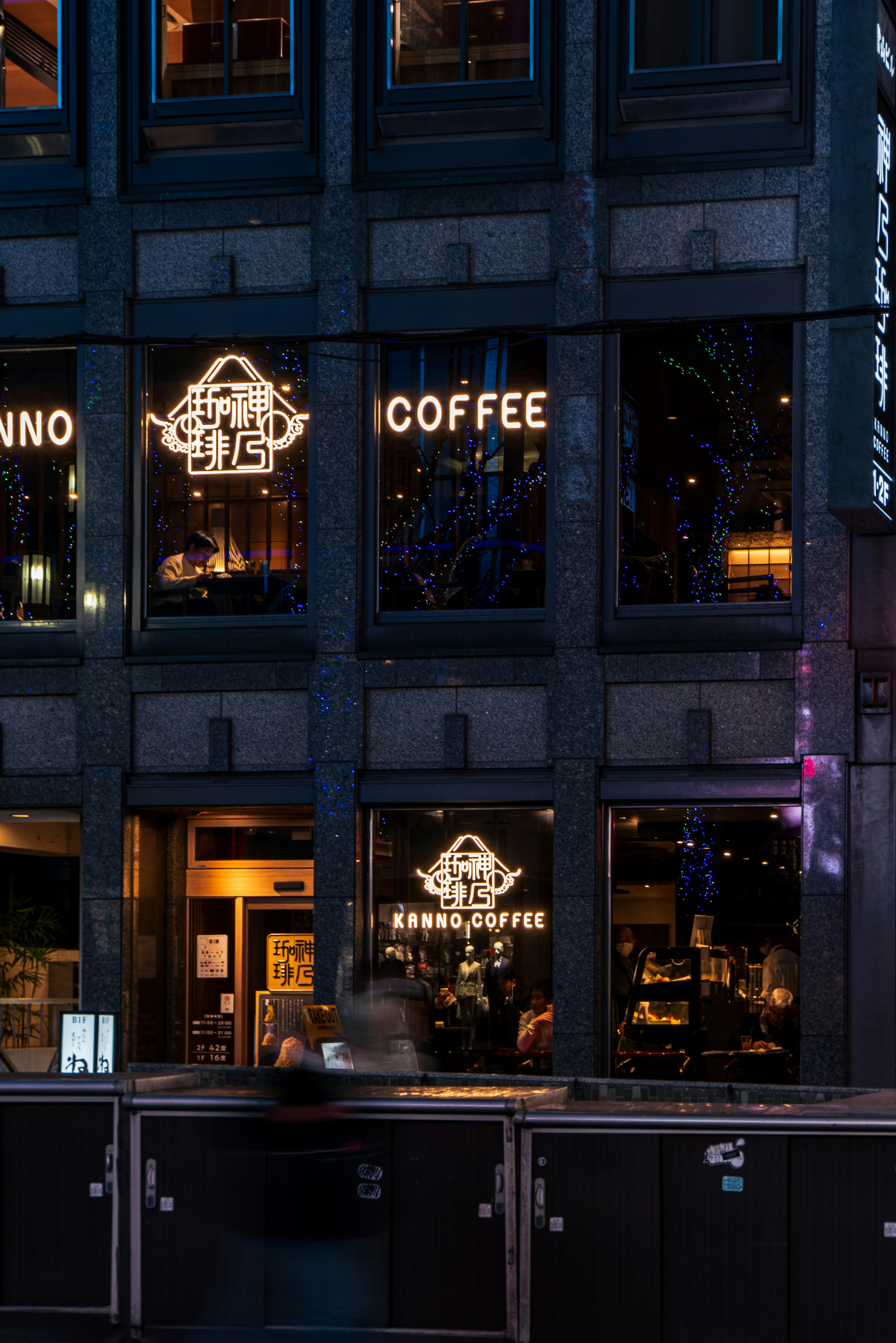 Exterior view of a coffee shop with illuminated signage in a dark setting