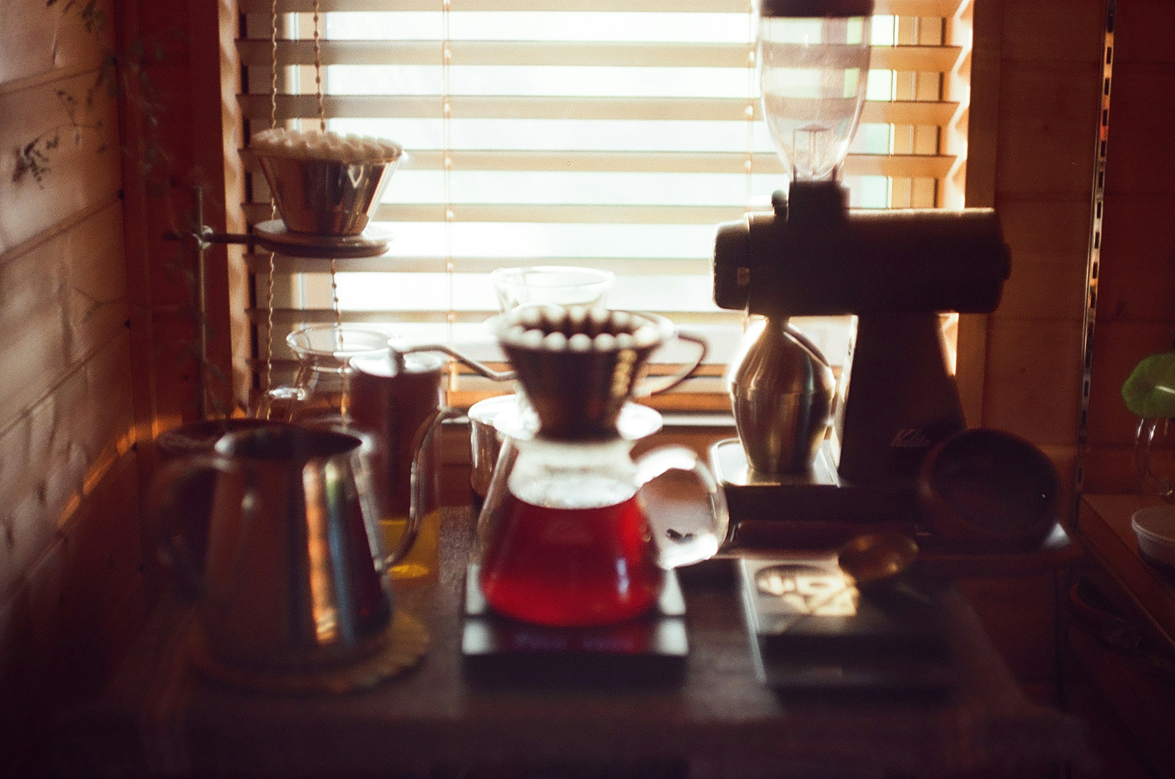 Interior de una cafetería con equipo de café y paredes de madera iluminadas por persianas