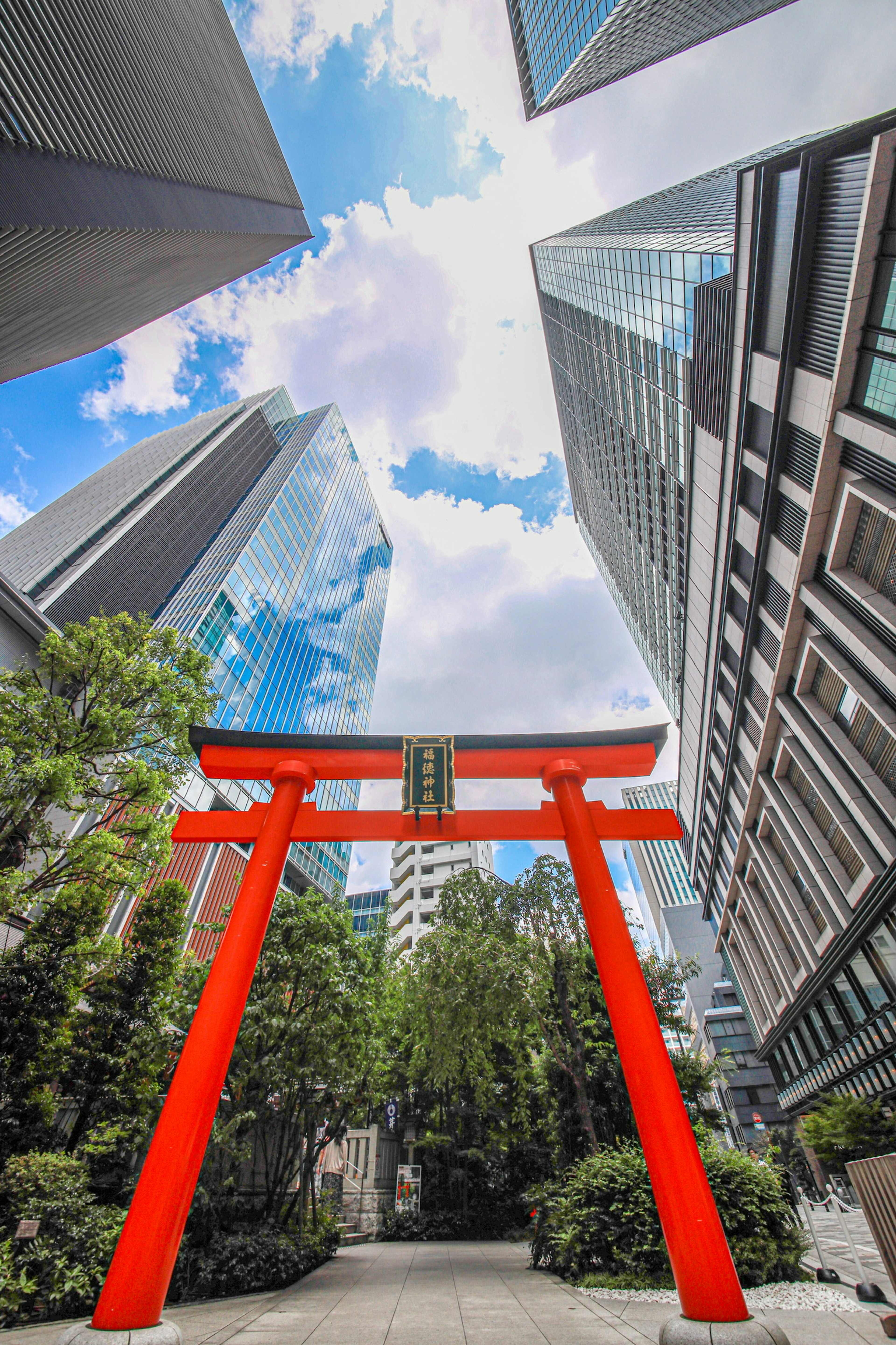 高層ビルに囲まれた赤い鳥居と青空