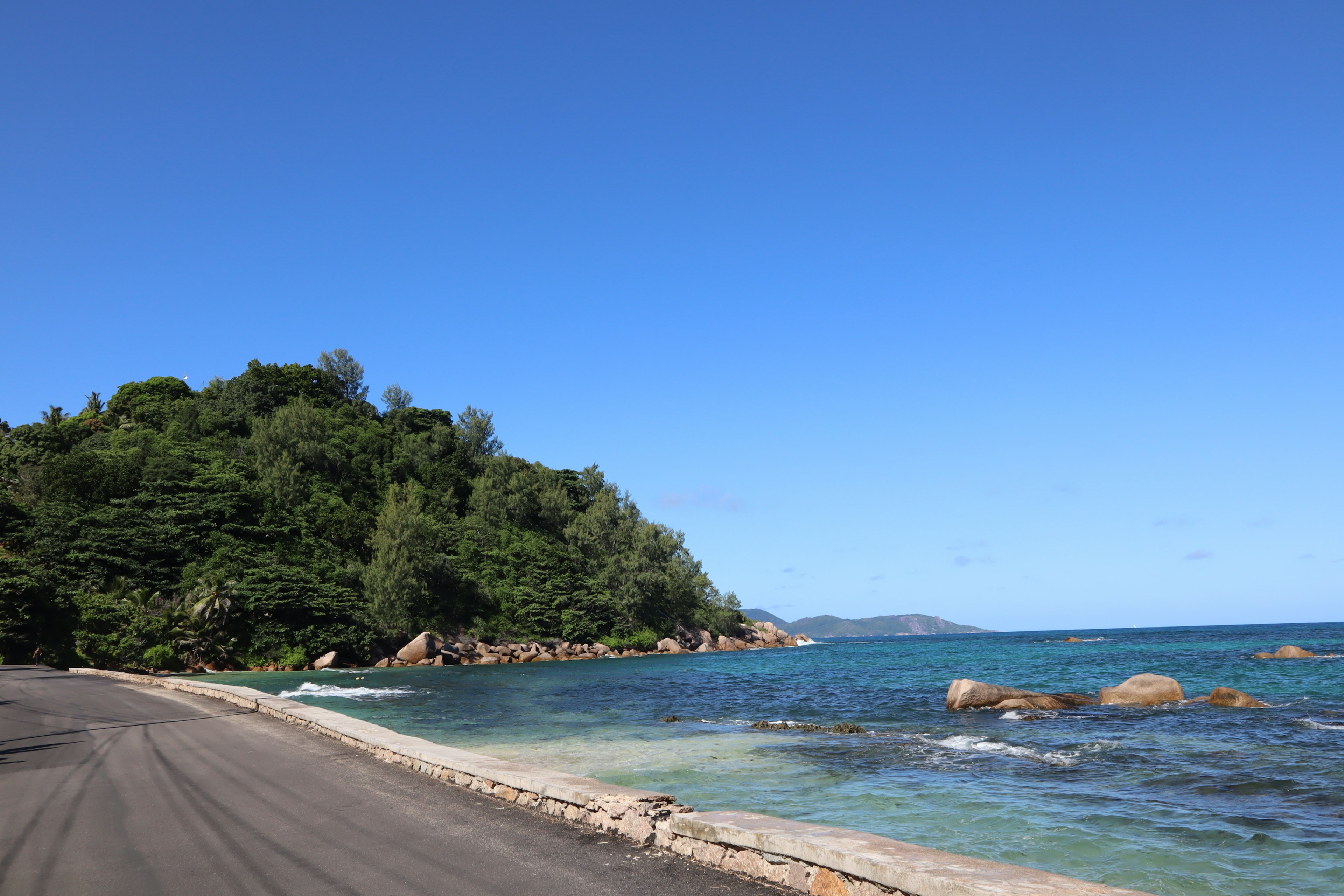 Vue panoramique d'une route côtière avec des collines verdoyantes et une eau bleue claire