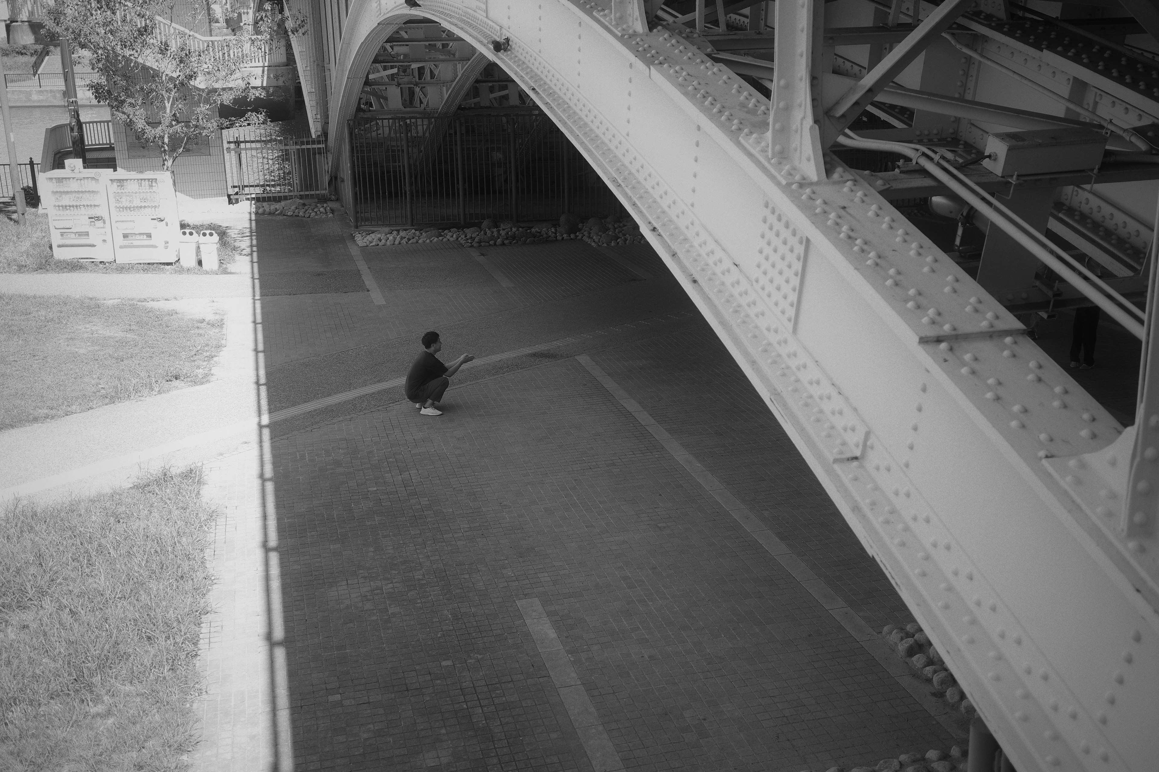 Une personne assise sous un pont noir et blanc