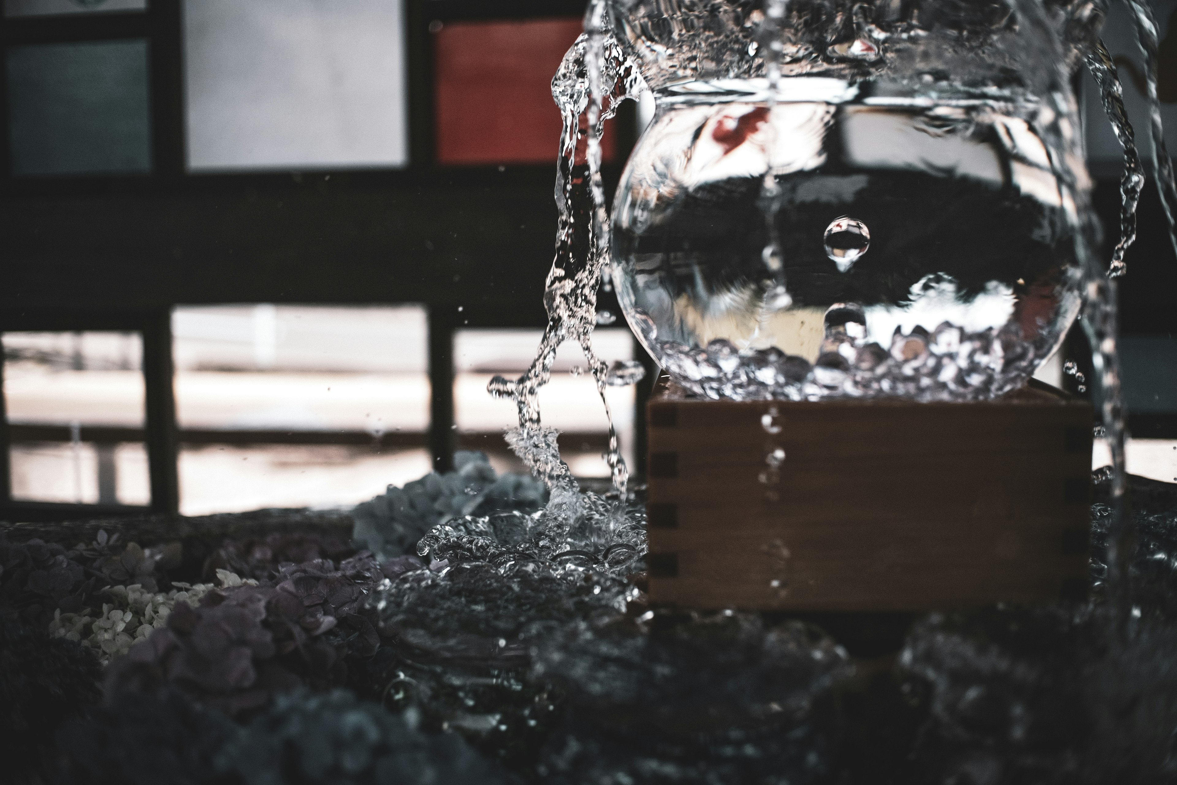 Glass bowl filled with water on a wooden base with flowing water