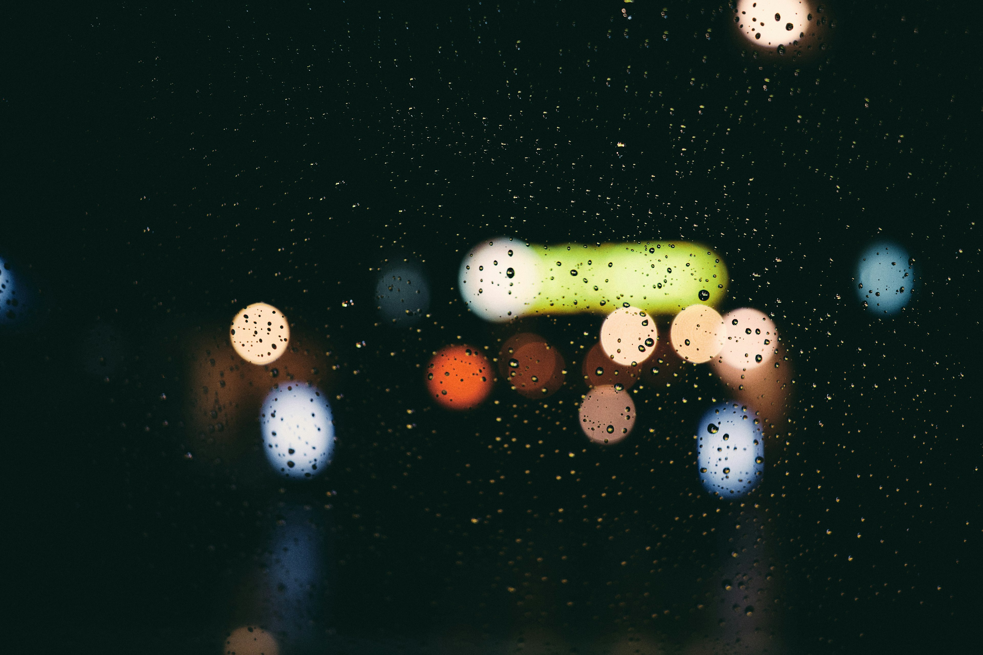 Close-up of blurred city lights through rain droplets