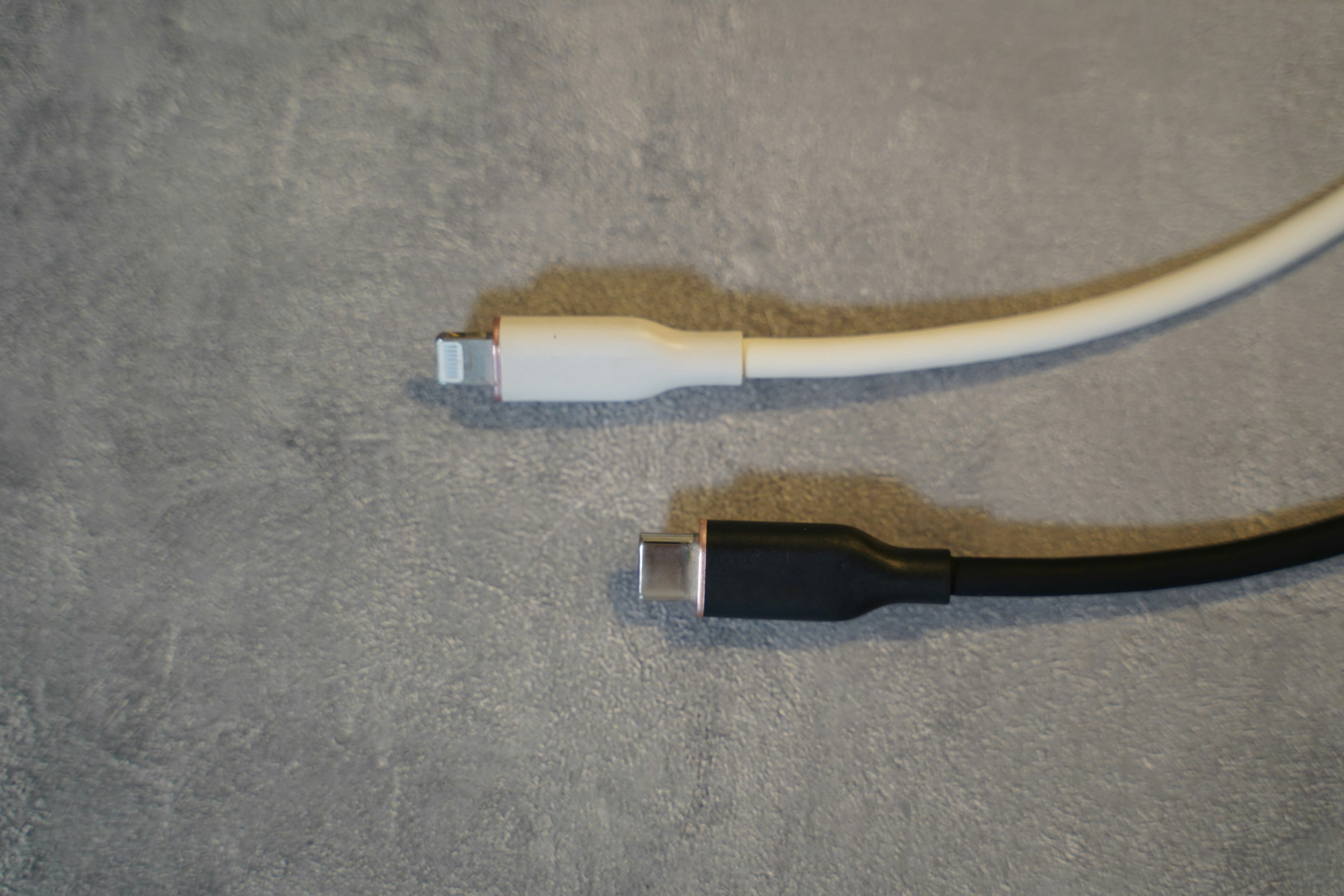 White and black USB cables resting on a concrete surface