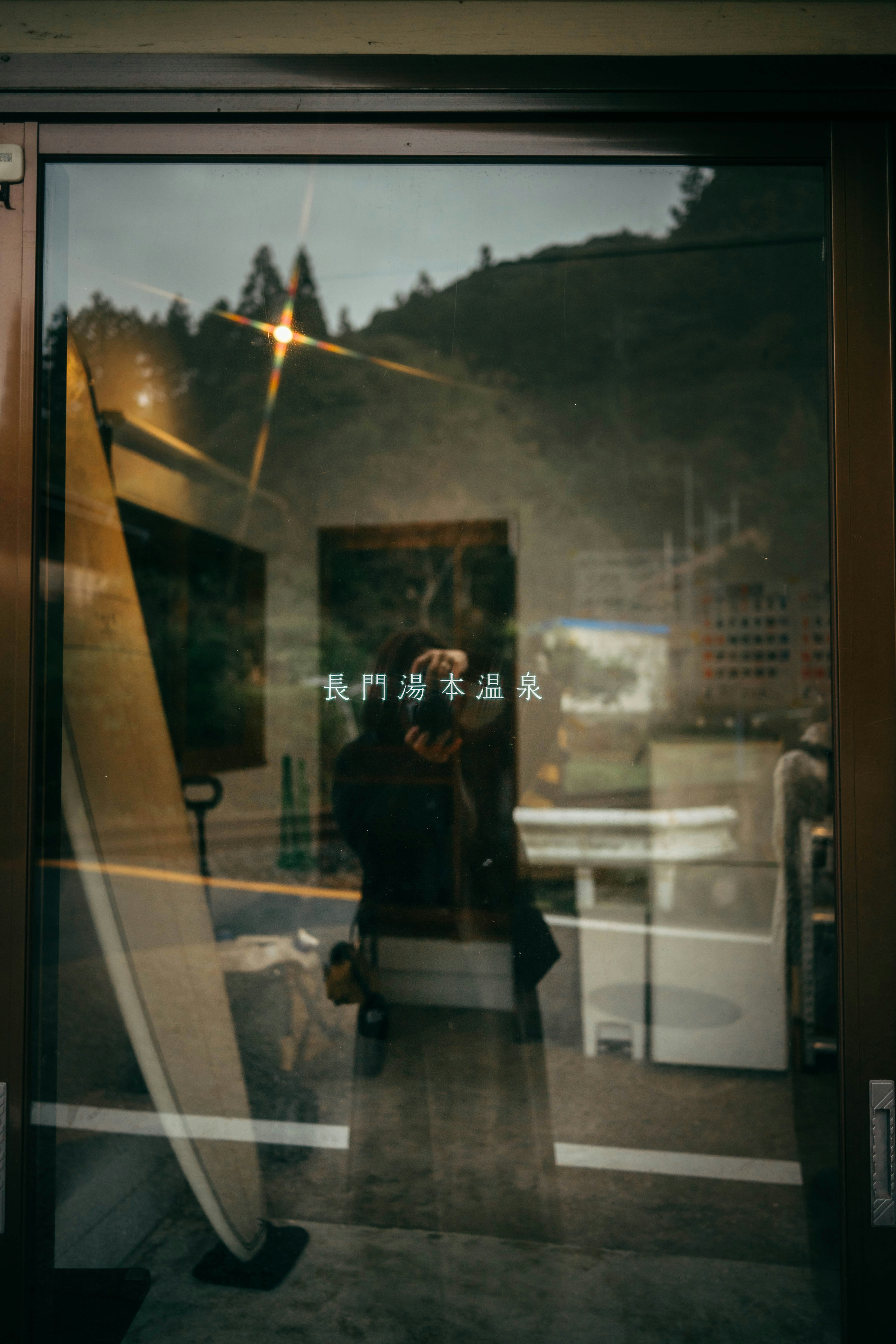 Reflexion einer Person und Landschaft auf einer Glastür