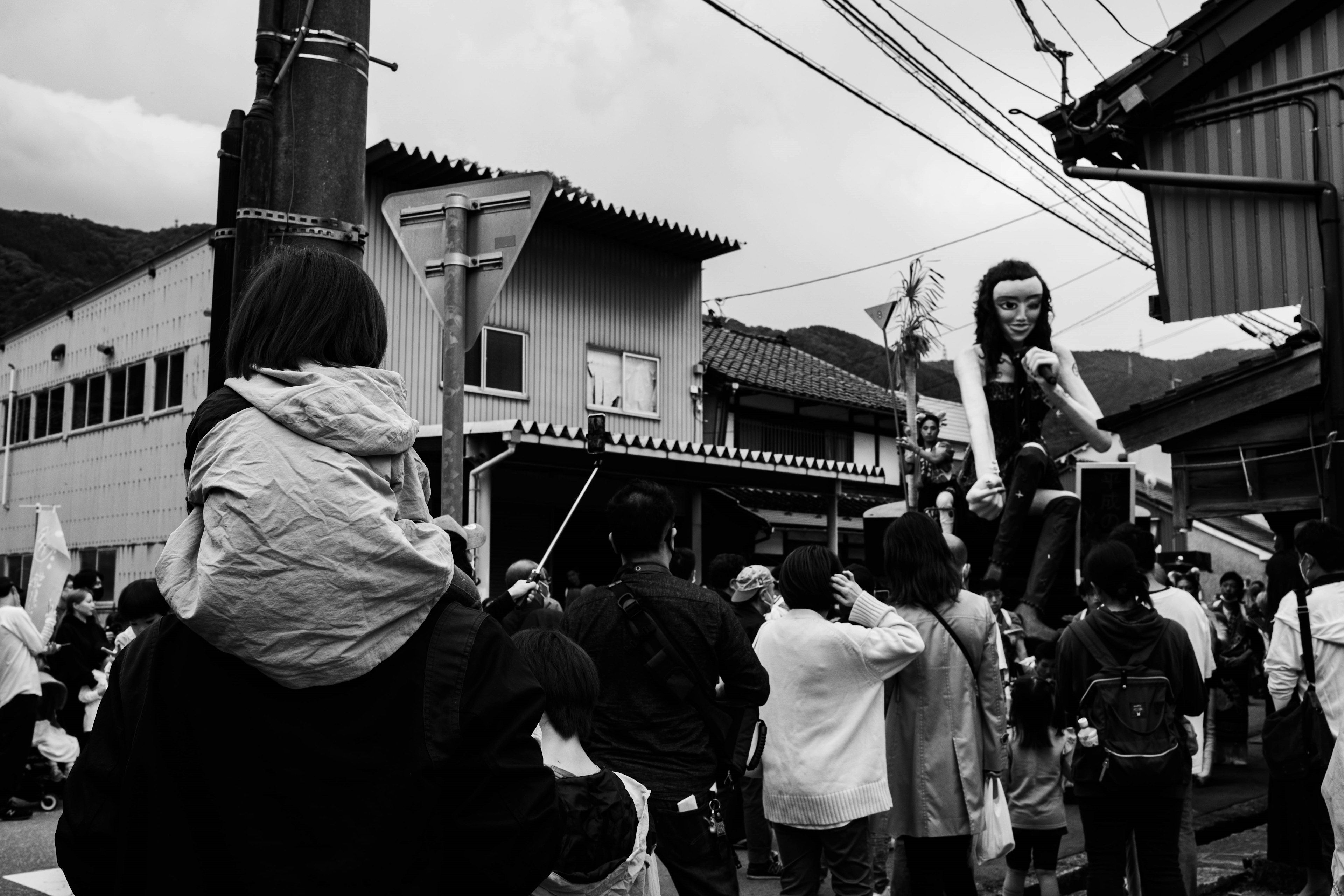 Crowd gathered at a black and white street festival with buildings and power lines