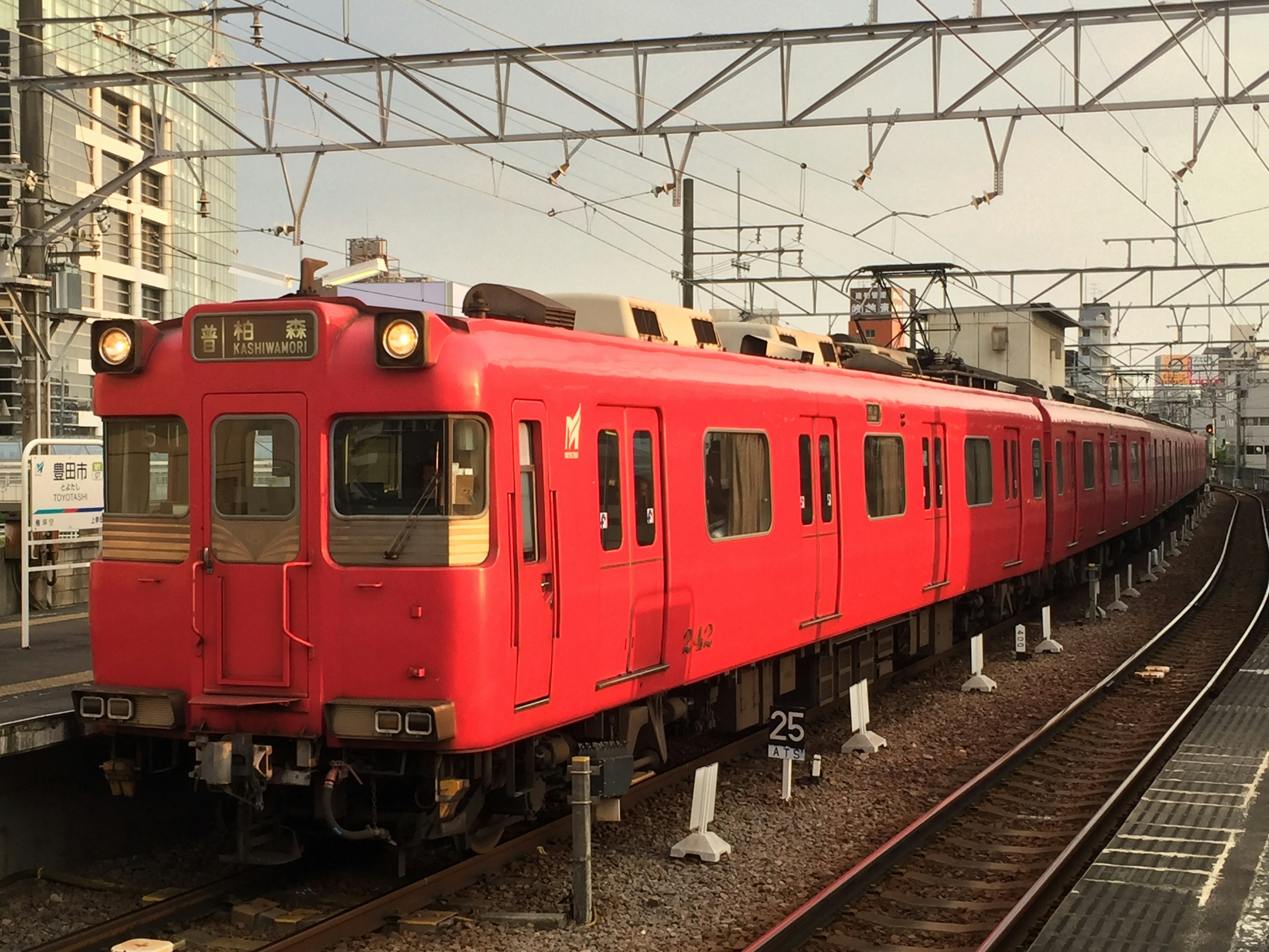 Red train parked at a station with urban background