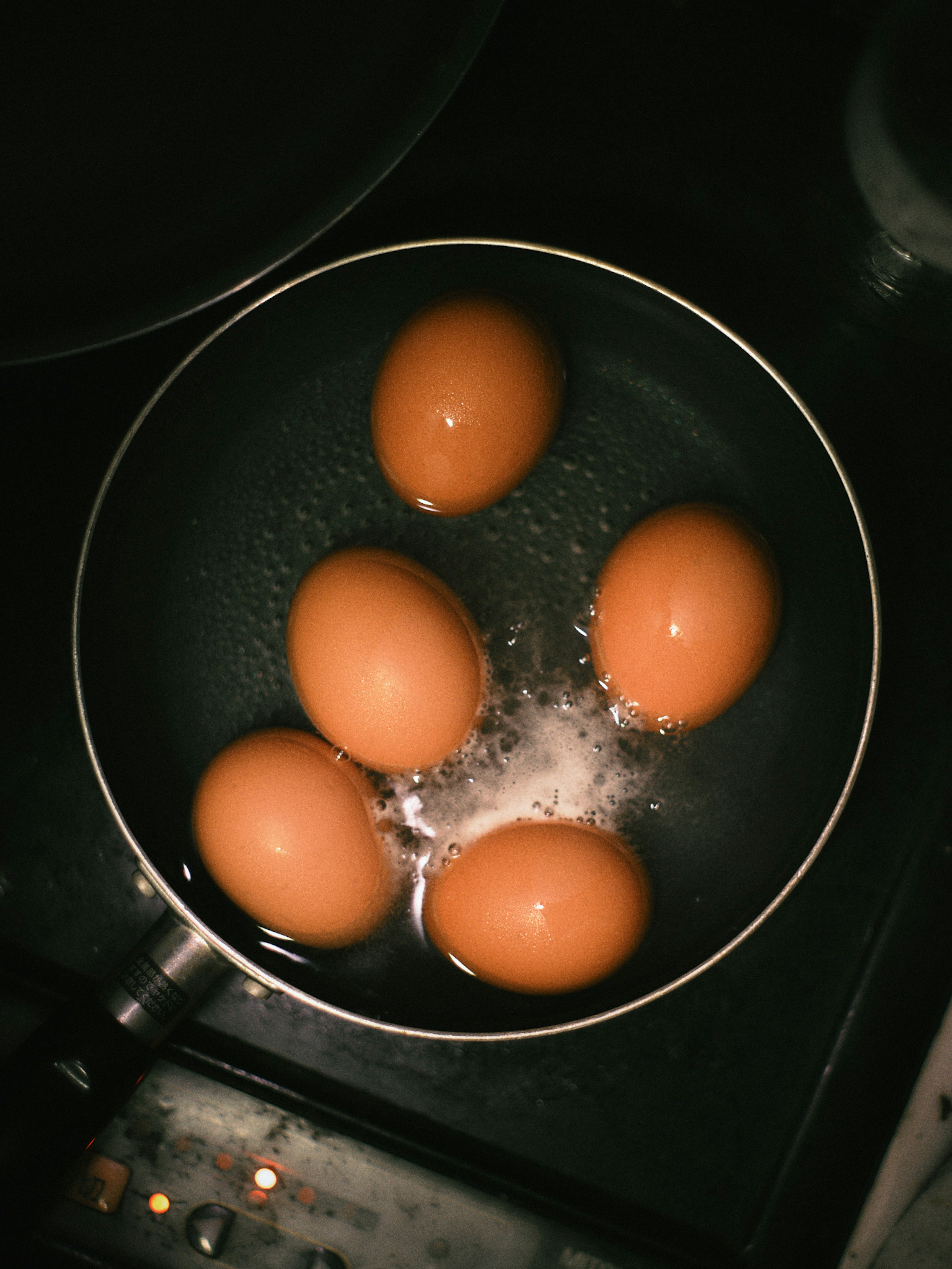 Fünf Eier, die in einem Topf auf dem Herd kochen