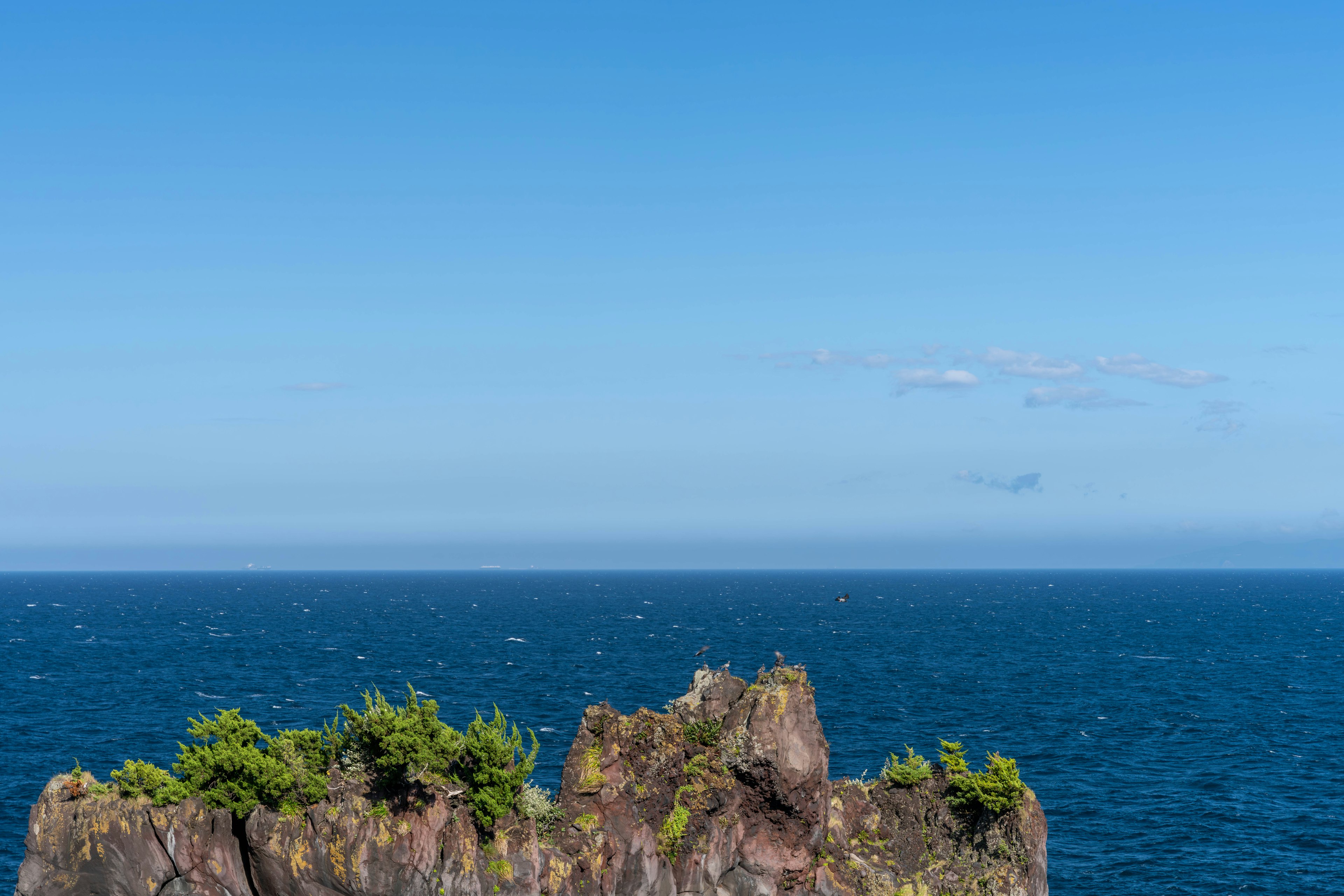 Vista escénica de una costa rocosa bajo un cielo azul claro y el océano