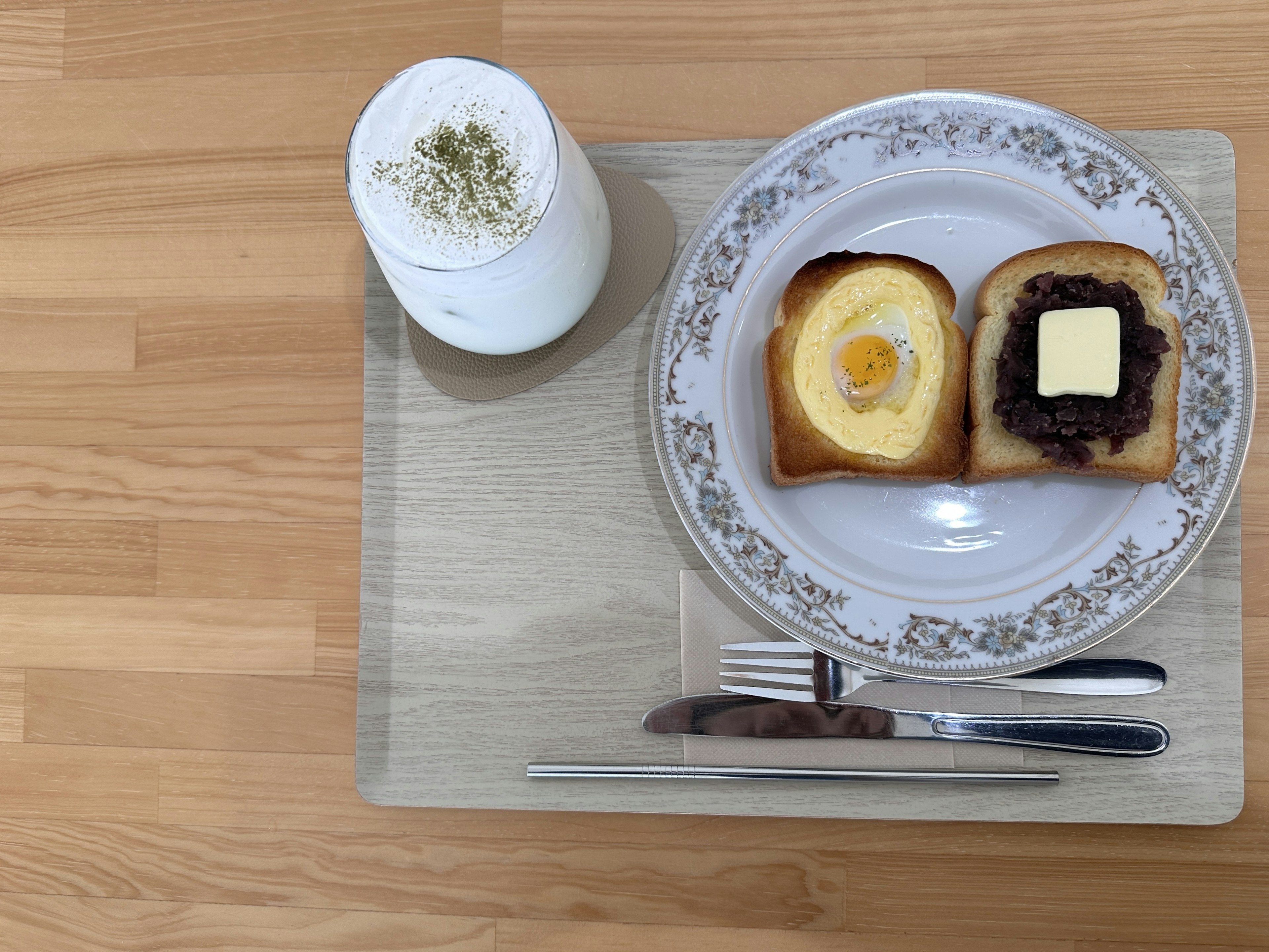 Frühstücksteller mit Toast belegt mit Ei und Butter neben einem Dessertgetränk