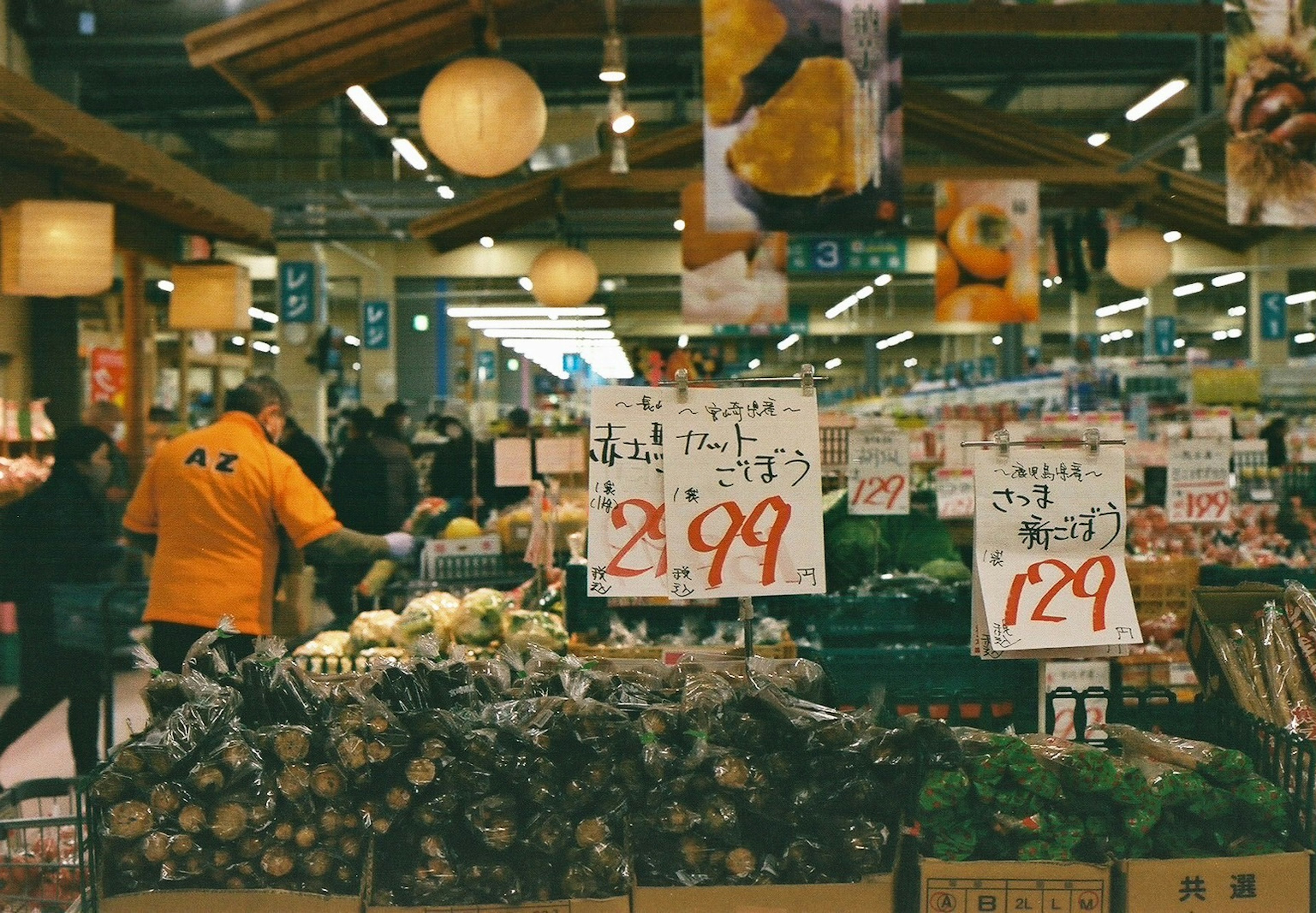 Menschen, die im Obst- und Gemüsebereich eines Supermarktes mit Preisschildern einkaufen