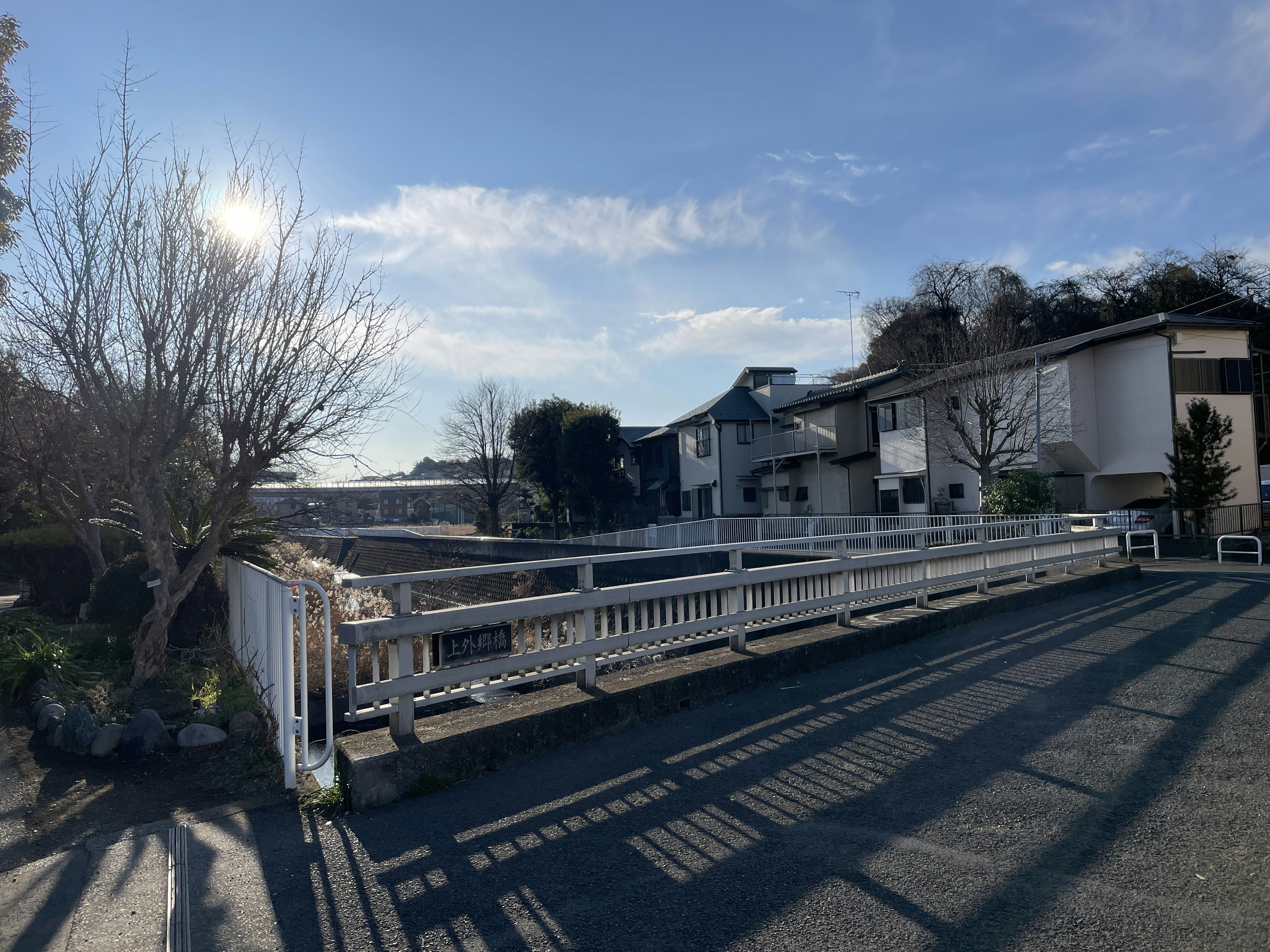 A bridge leading to a residential area under a blue sky