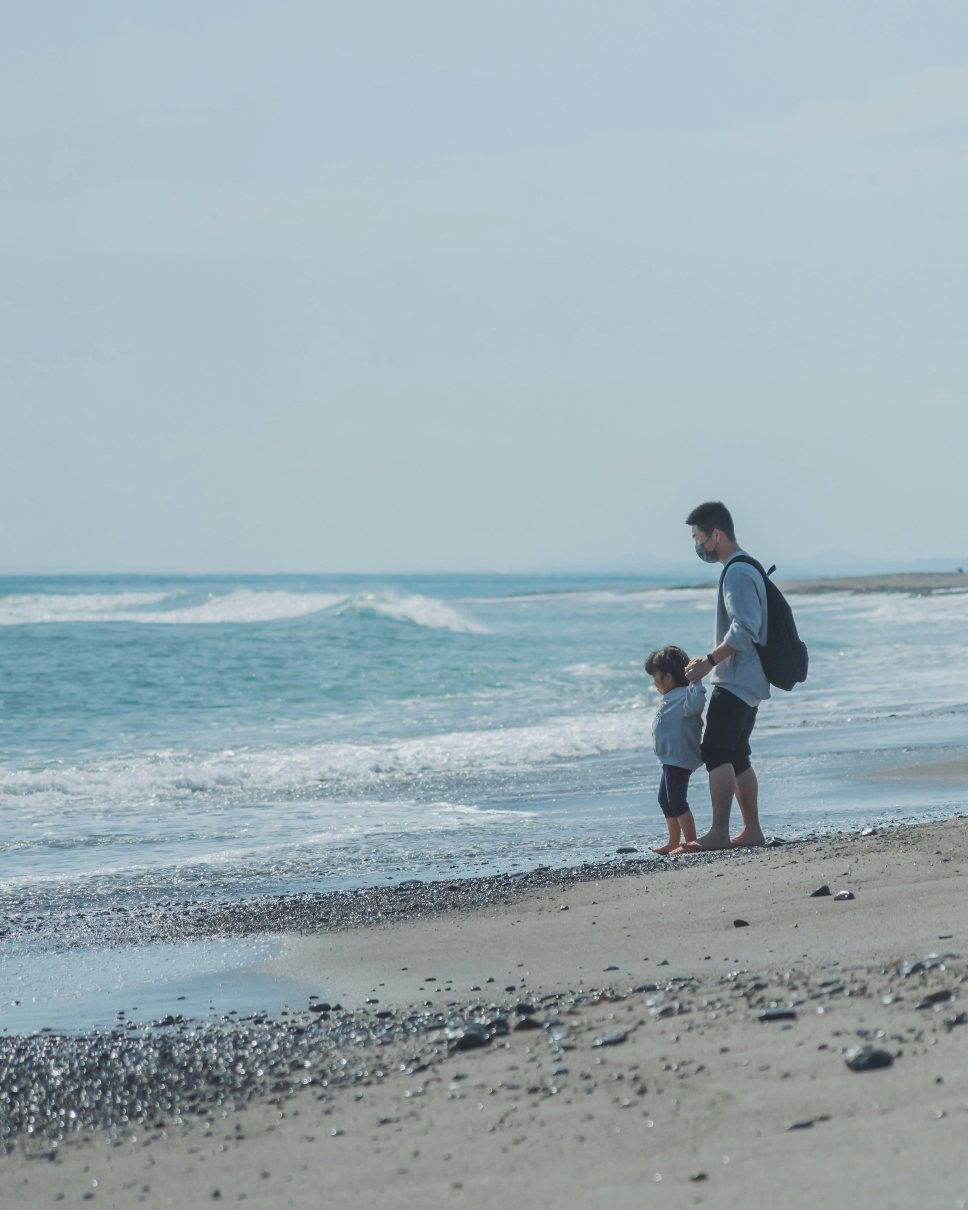 Vater steht mit Kind am Strand