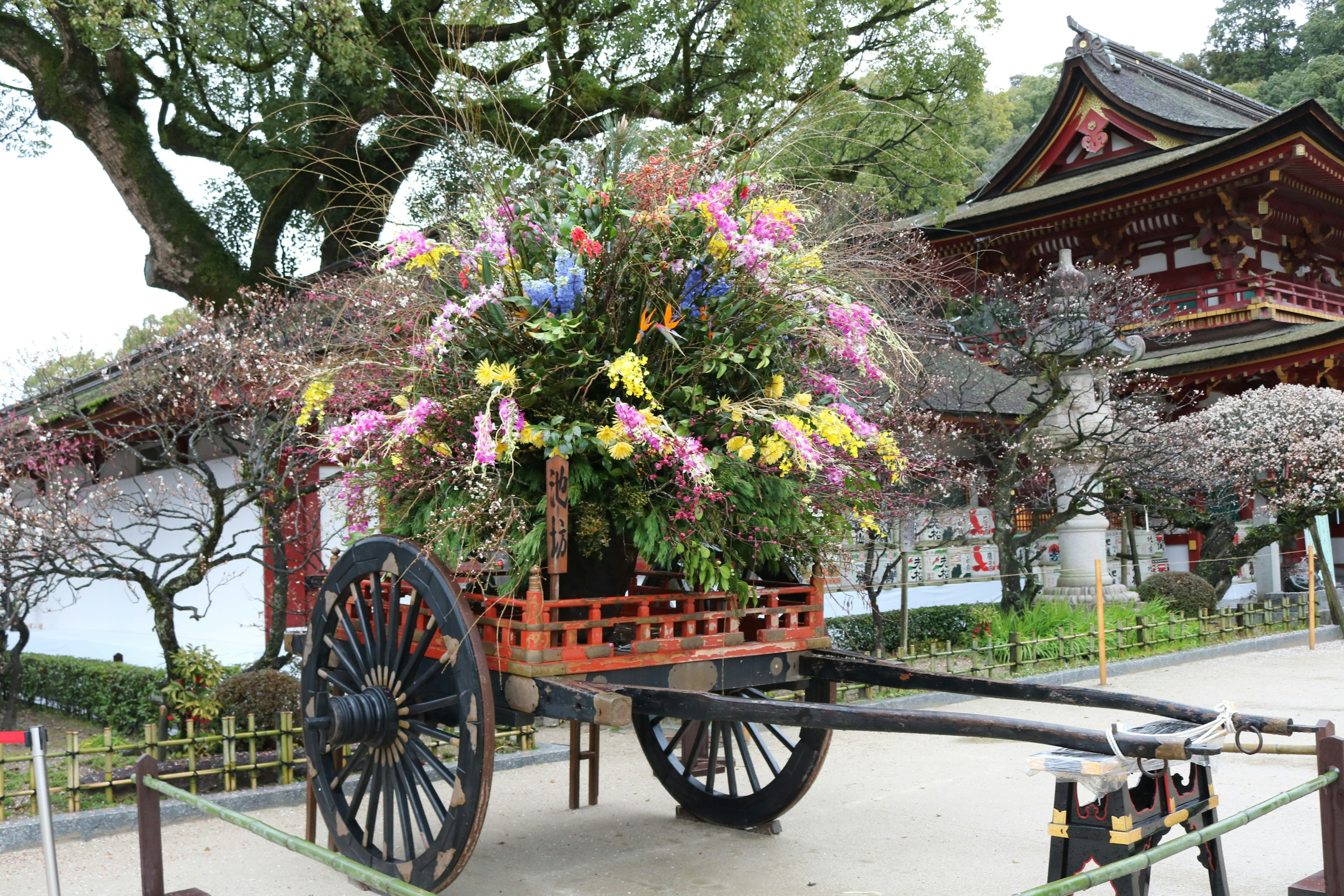 花が満載の伝統的な木製の車両と背景に日本の建物