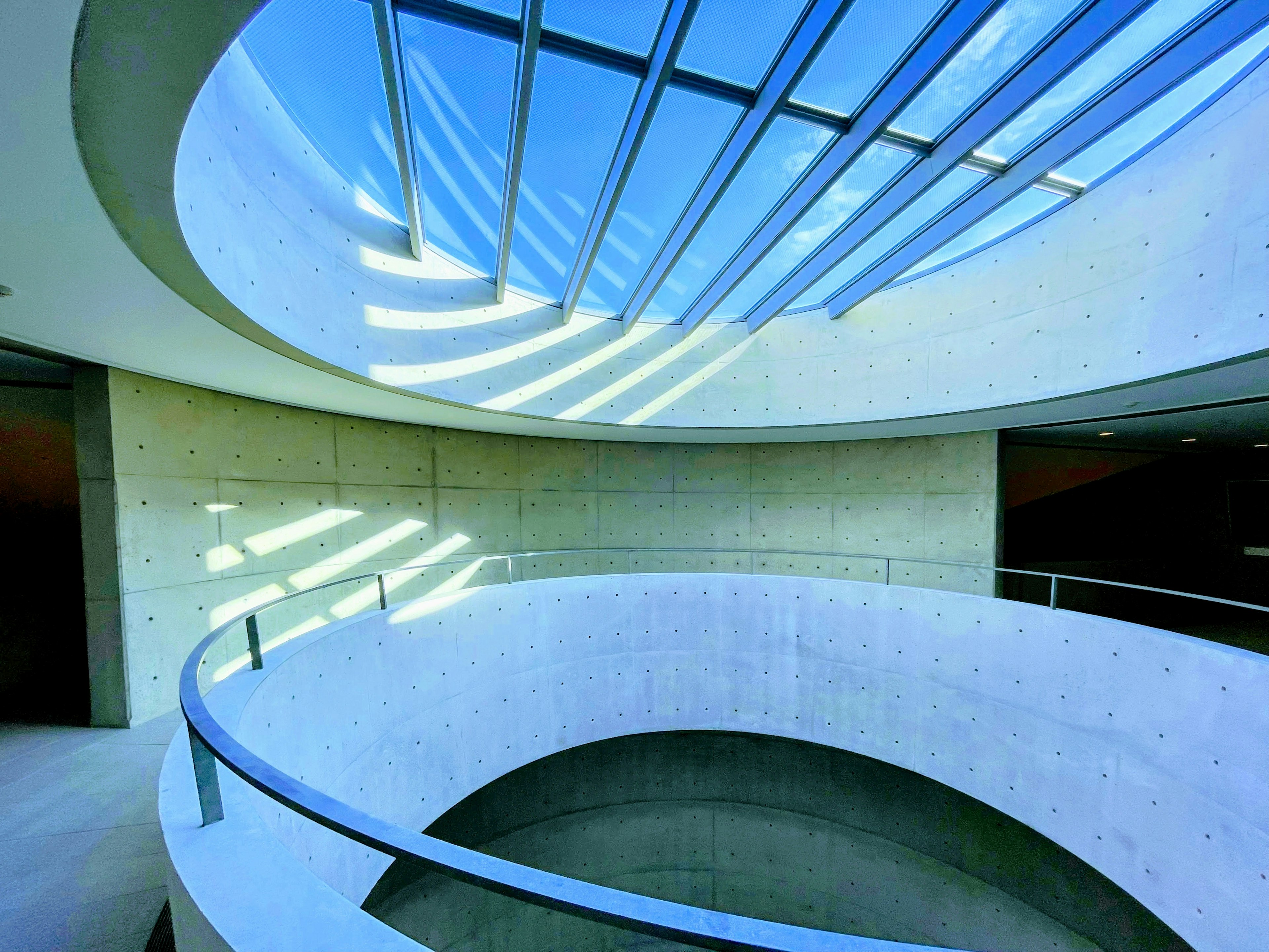 Interno di un edificio moderno con una scala curva e luce naturale da un soffitto in vetro