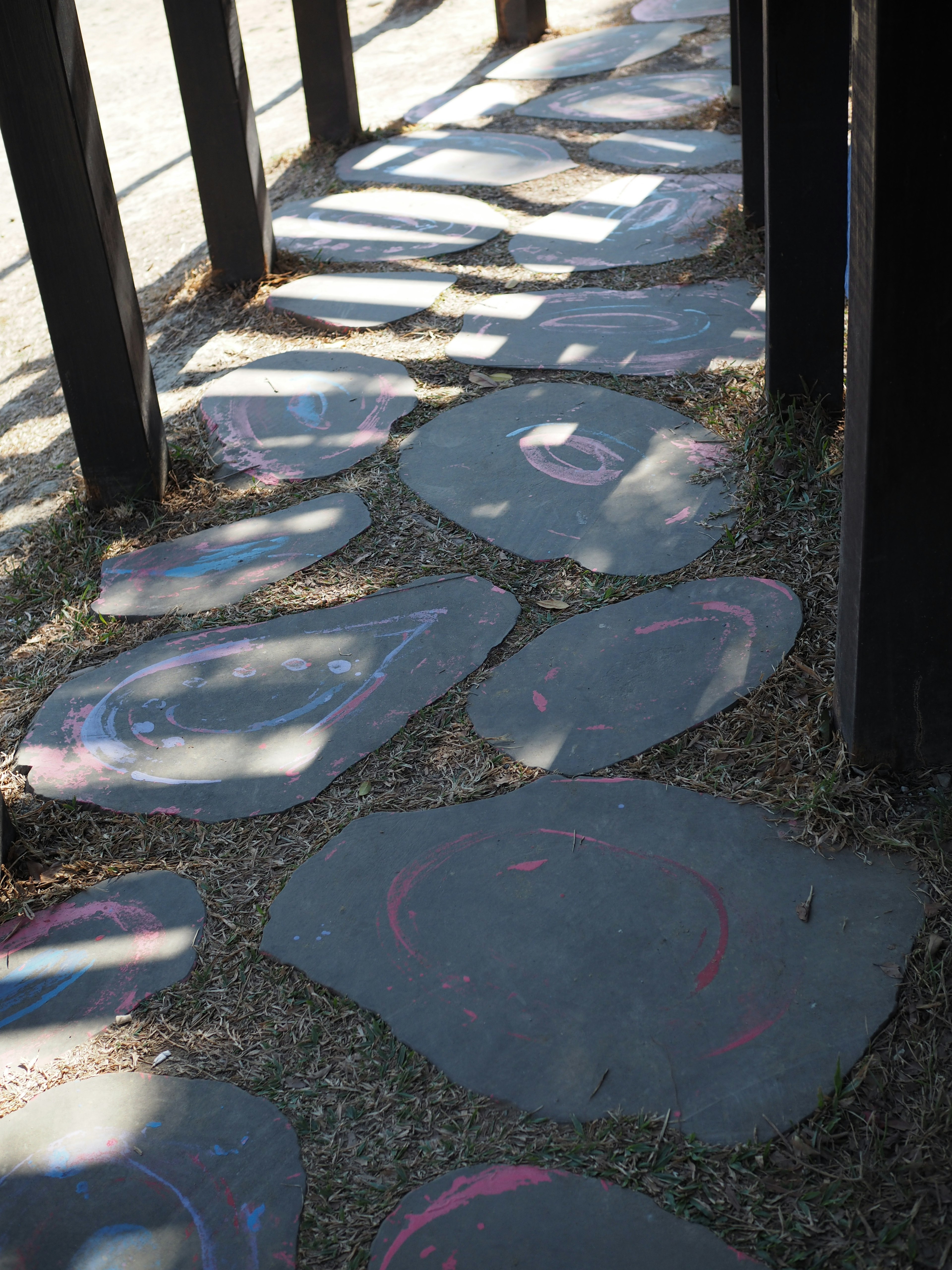 Colorful stone pathway between black wooden fence