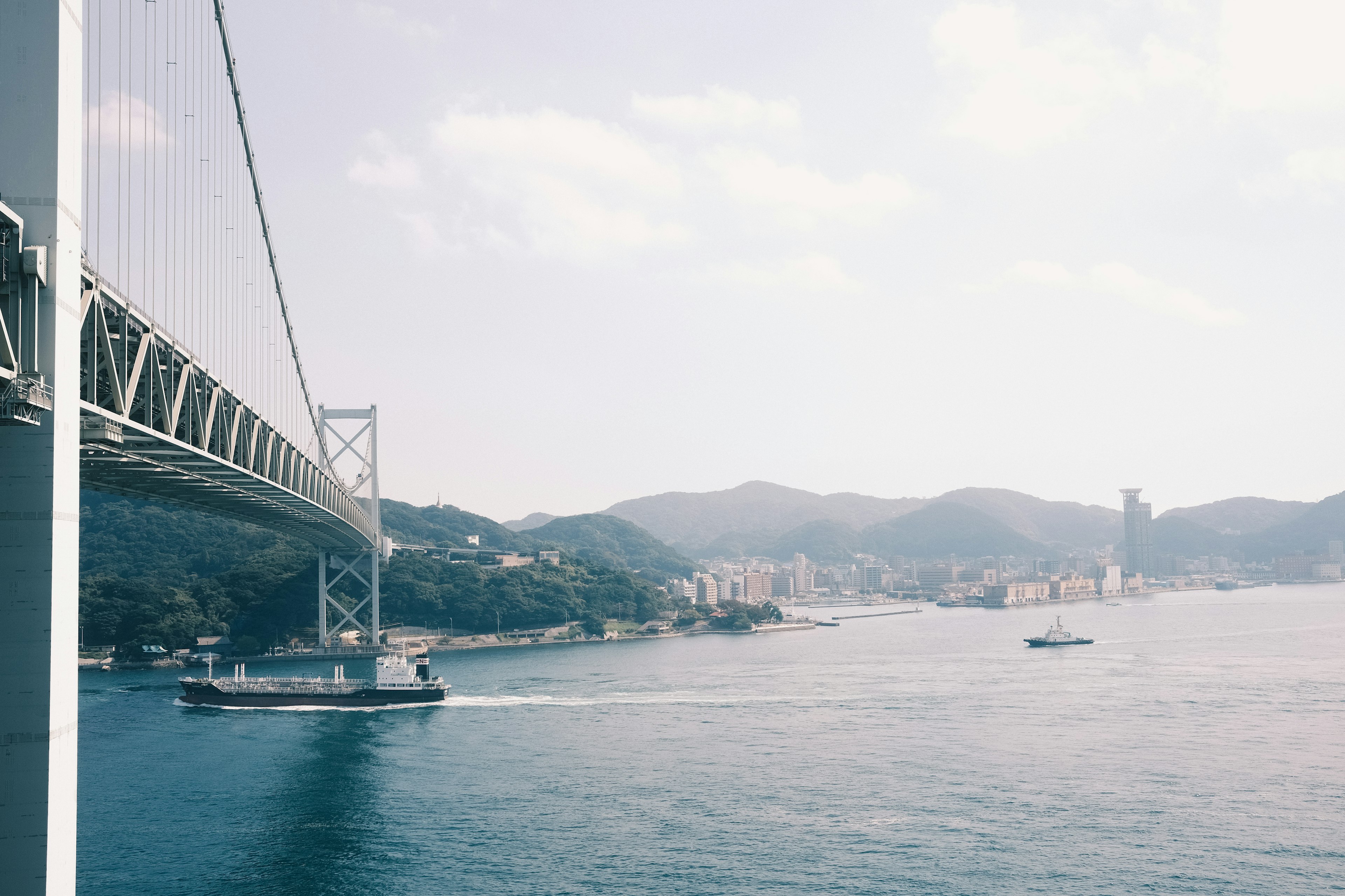 Un puente que se extiende sobre un hermoso paisaje marino con montañas al fondo