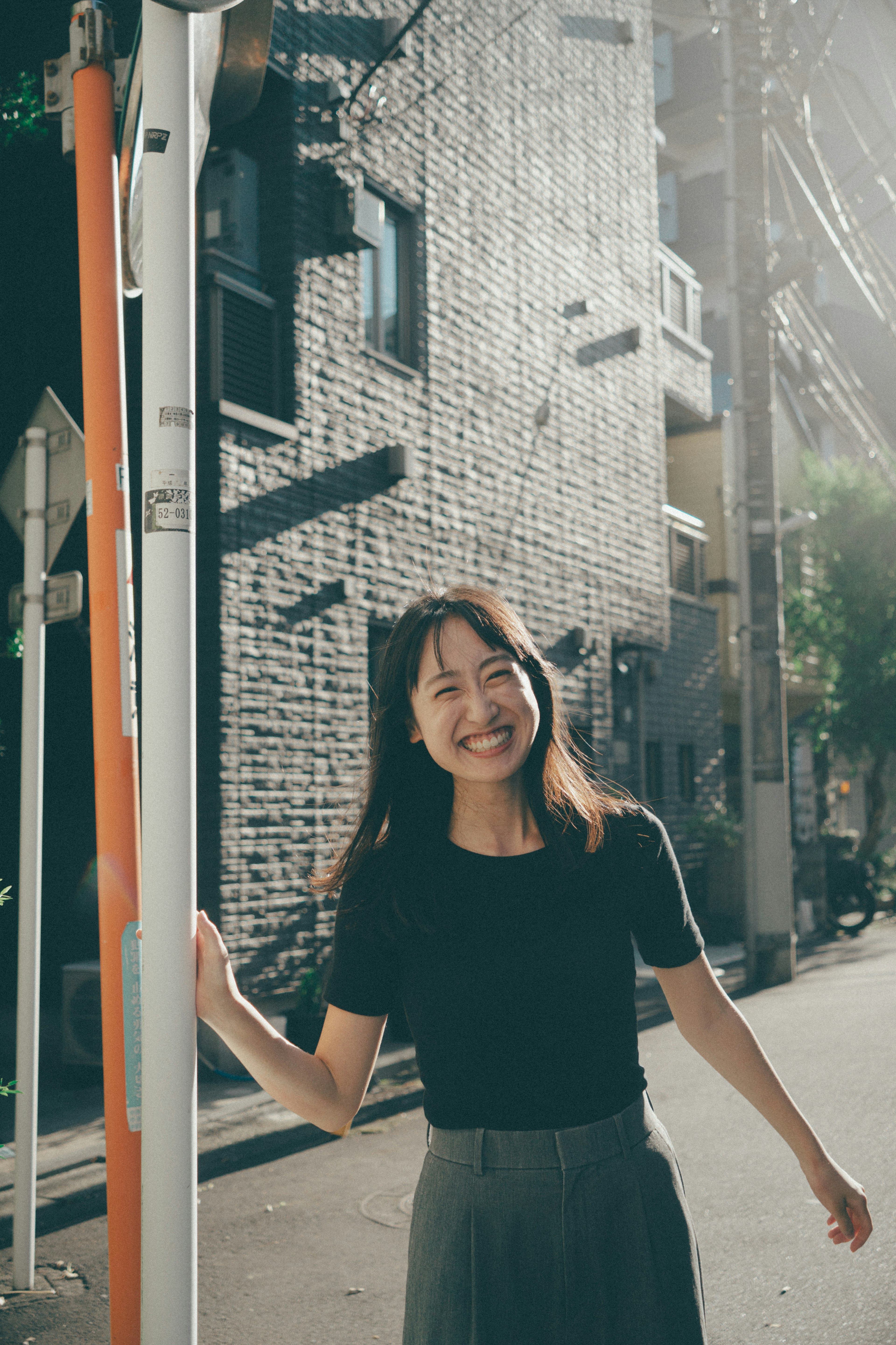 女性が街角で微笑んでいる姿 背景はレンガの壁と街の風景