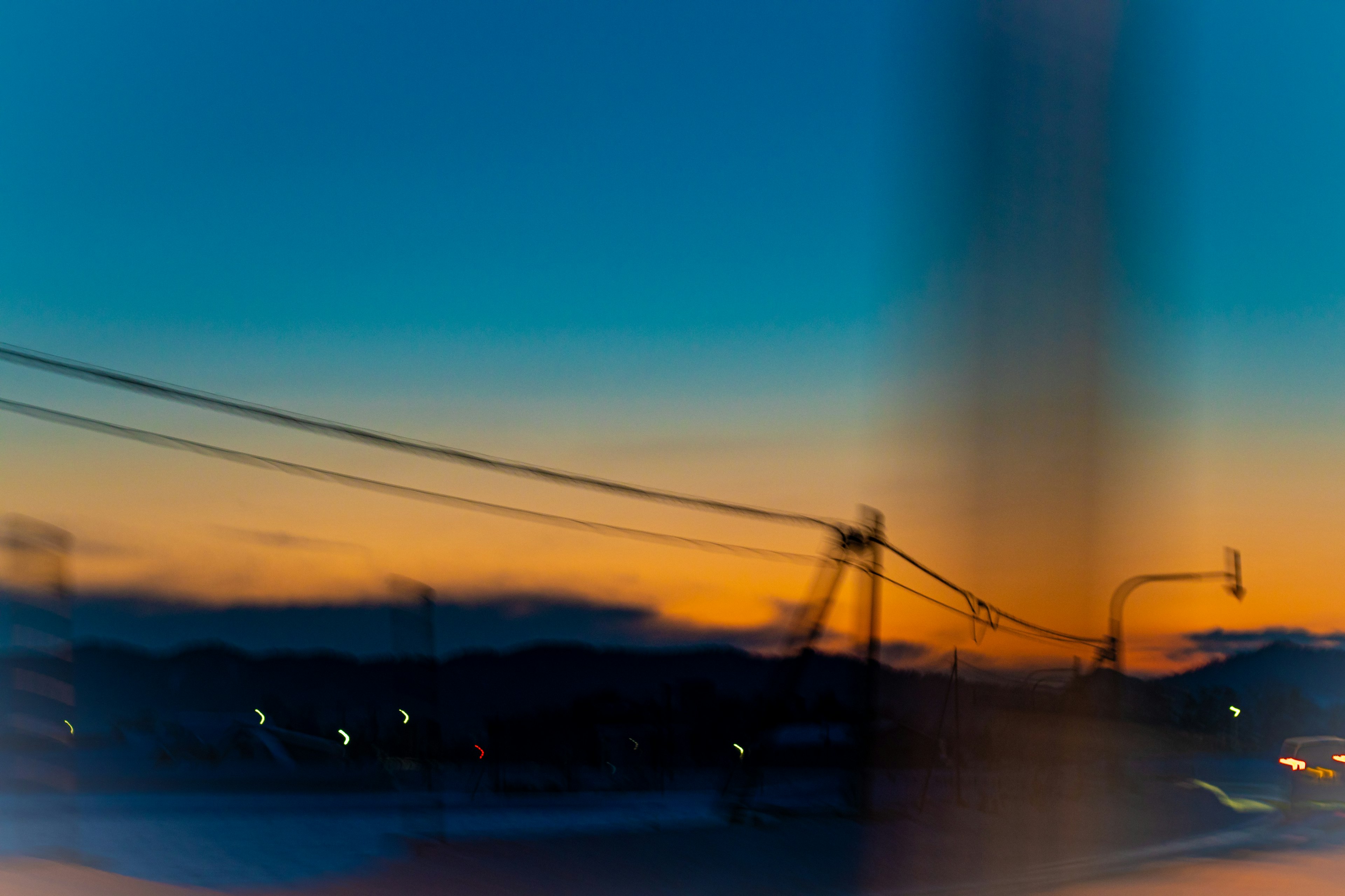 A blurred sunset view with blue and orange gradients featuring power lines