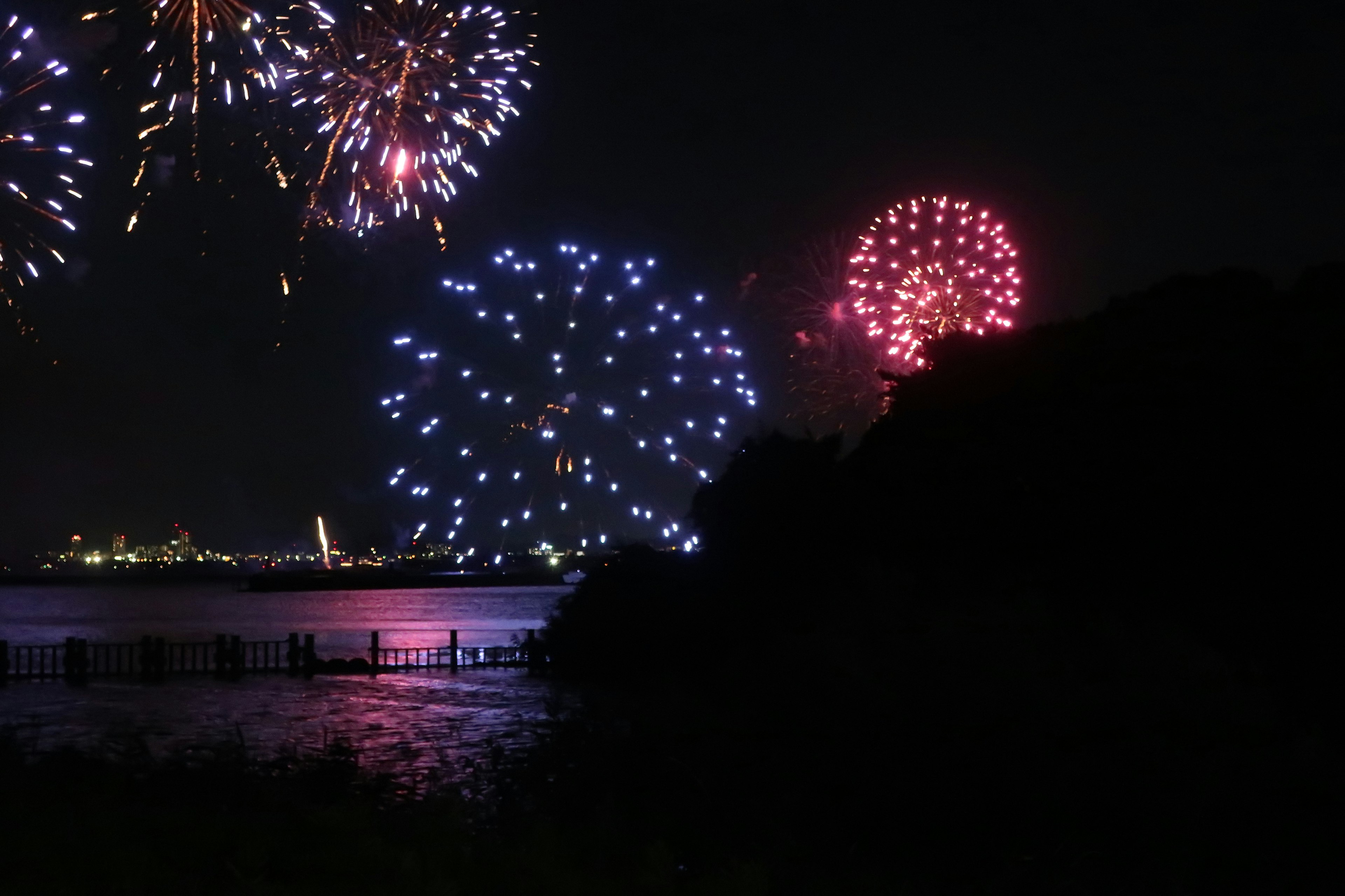 Colorful fireworks exploding in the night sky over a calm water surface