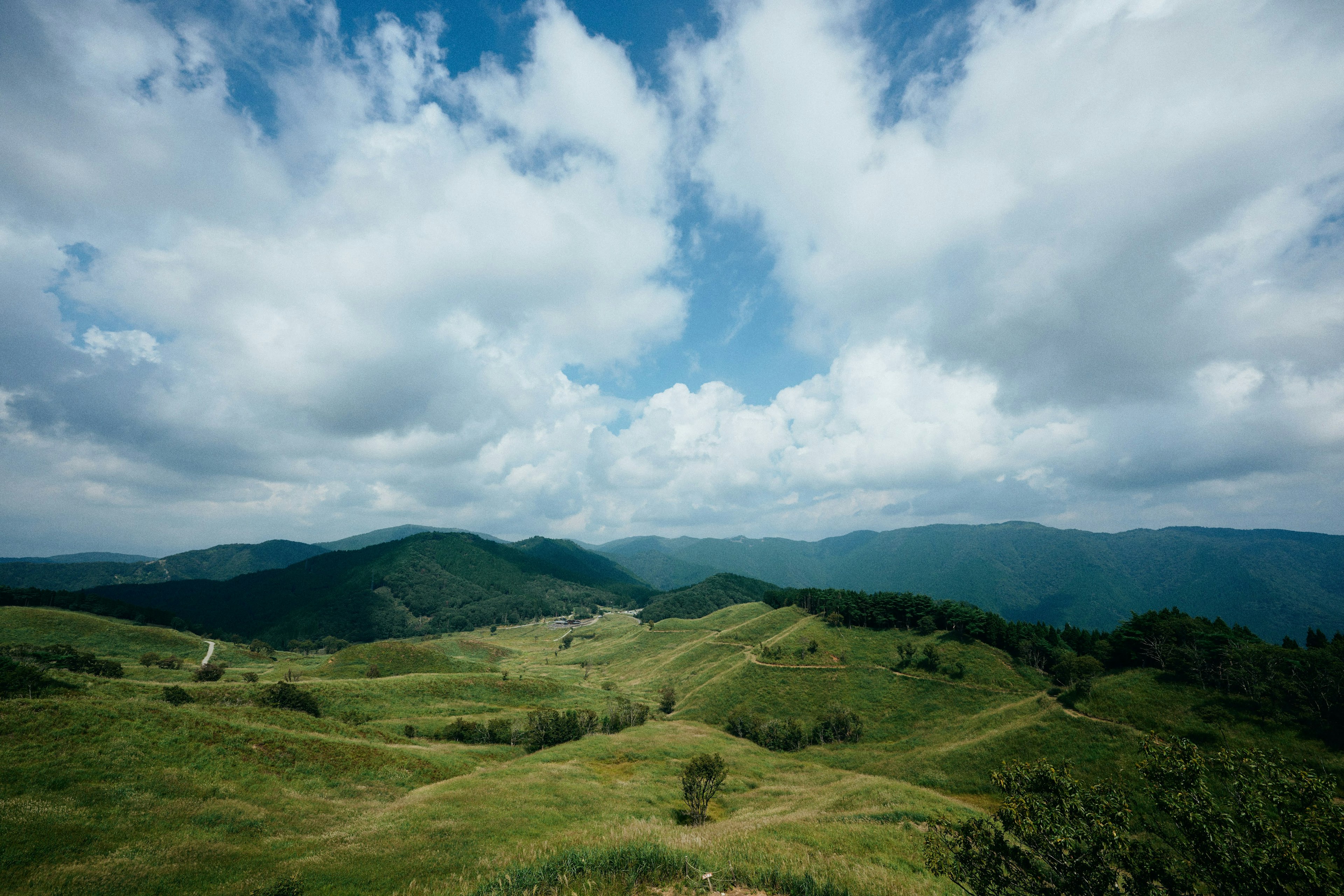 Colline verdi sotto un cielo azzurro con nuvole soffici