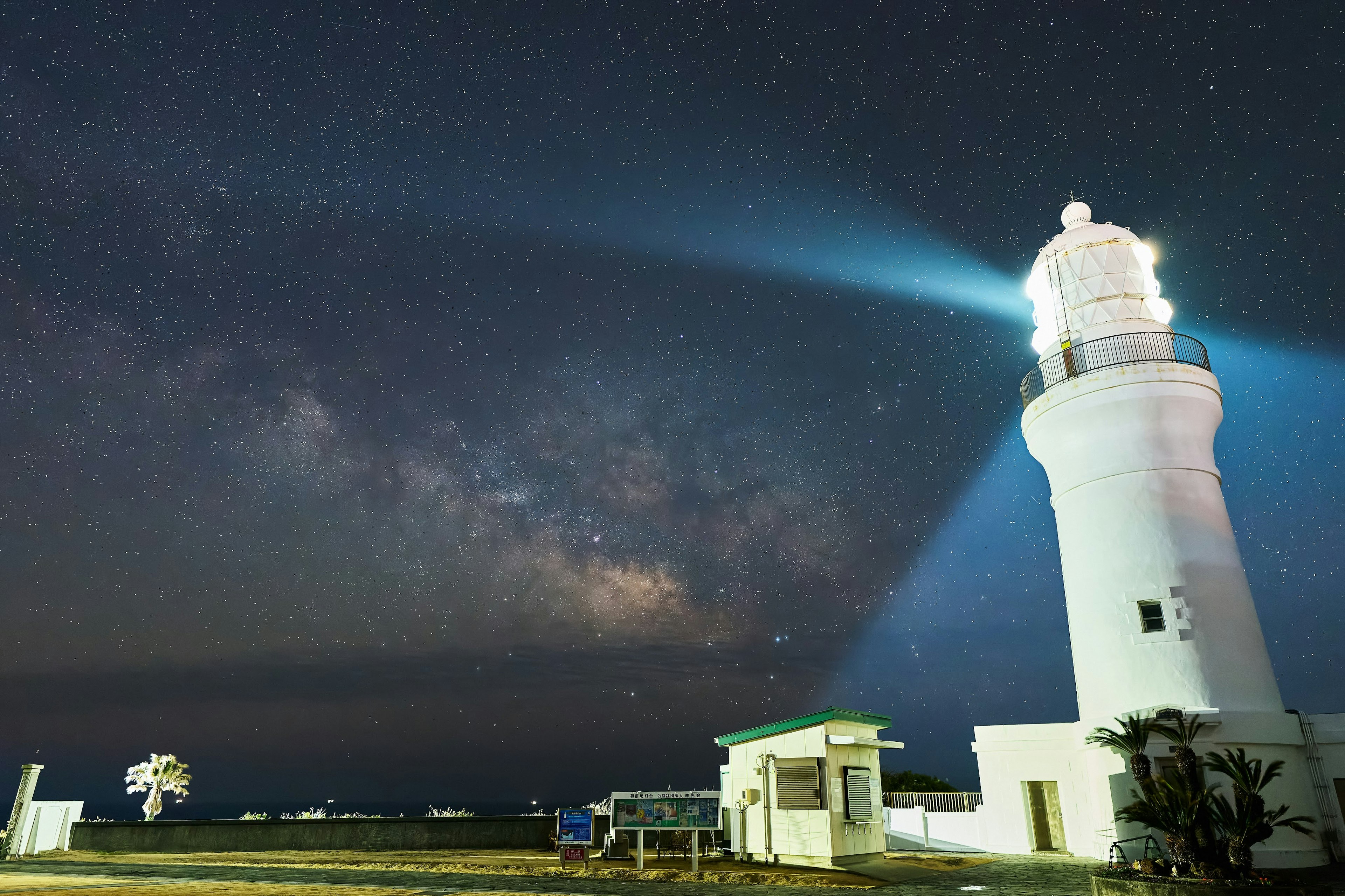 Phare sous un ciel étoilé avec des faisceaux lumineux