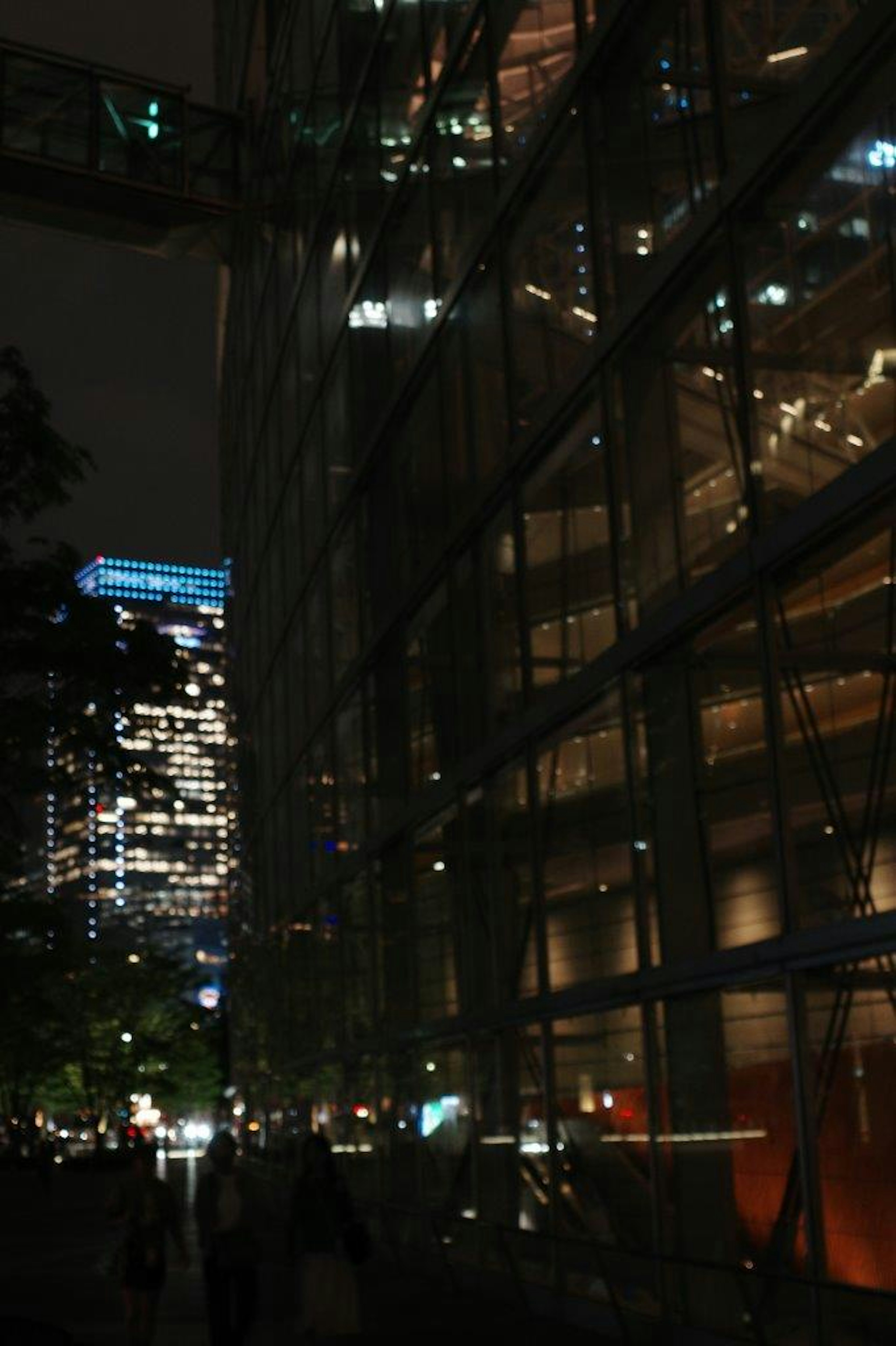 Beleuchtetes Glasgebäude in einer nächtlichen Stadlandschaft mit umliegenden Lichtern