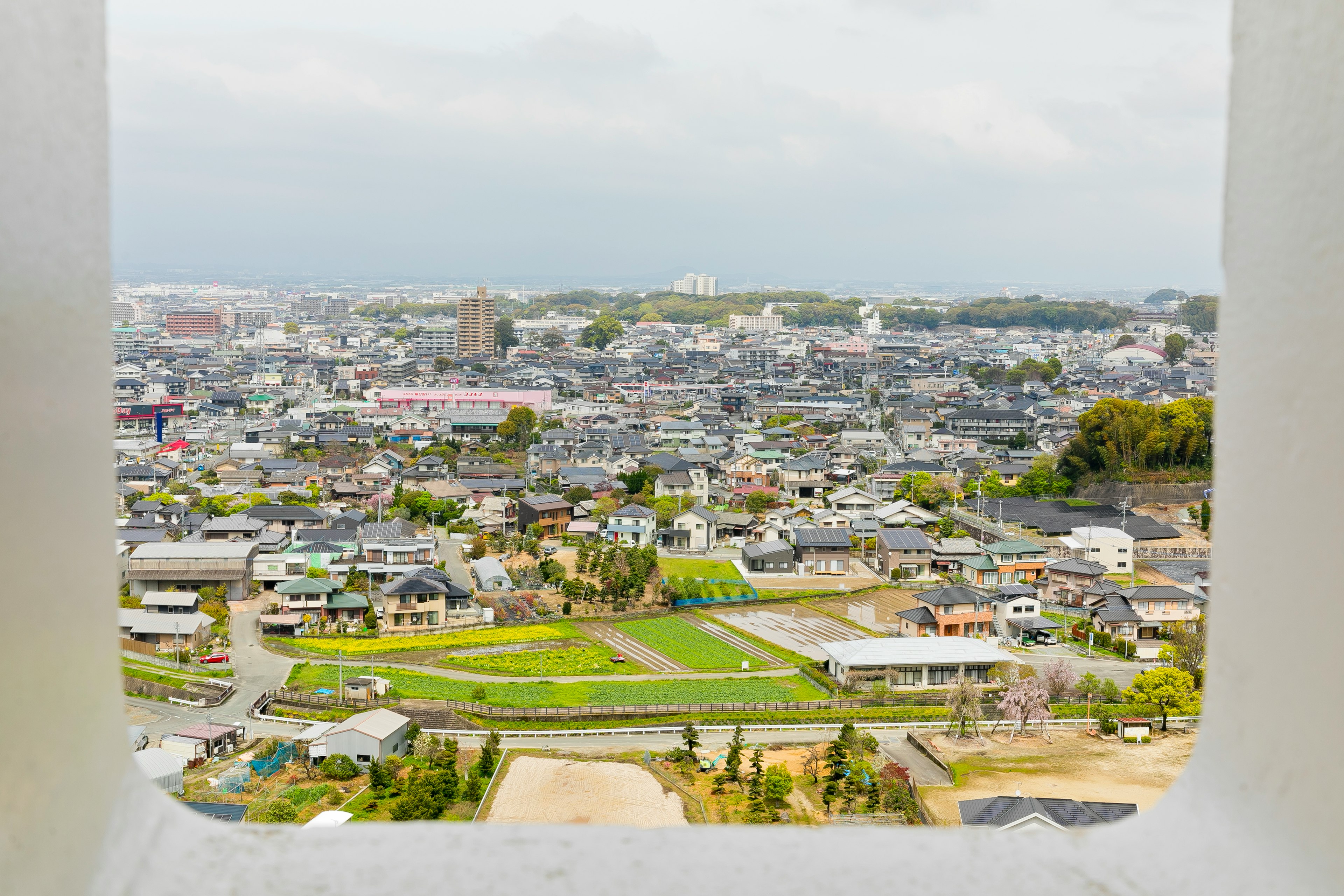 山の上からの眺めで、住宅地と緑の公園が広がる風景