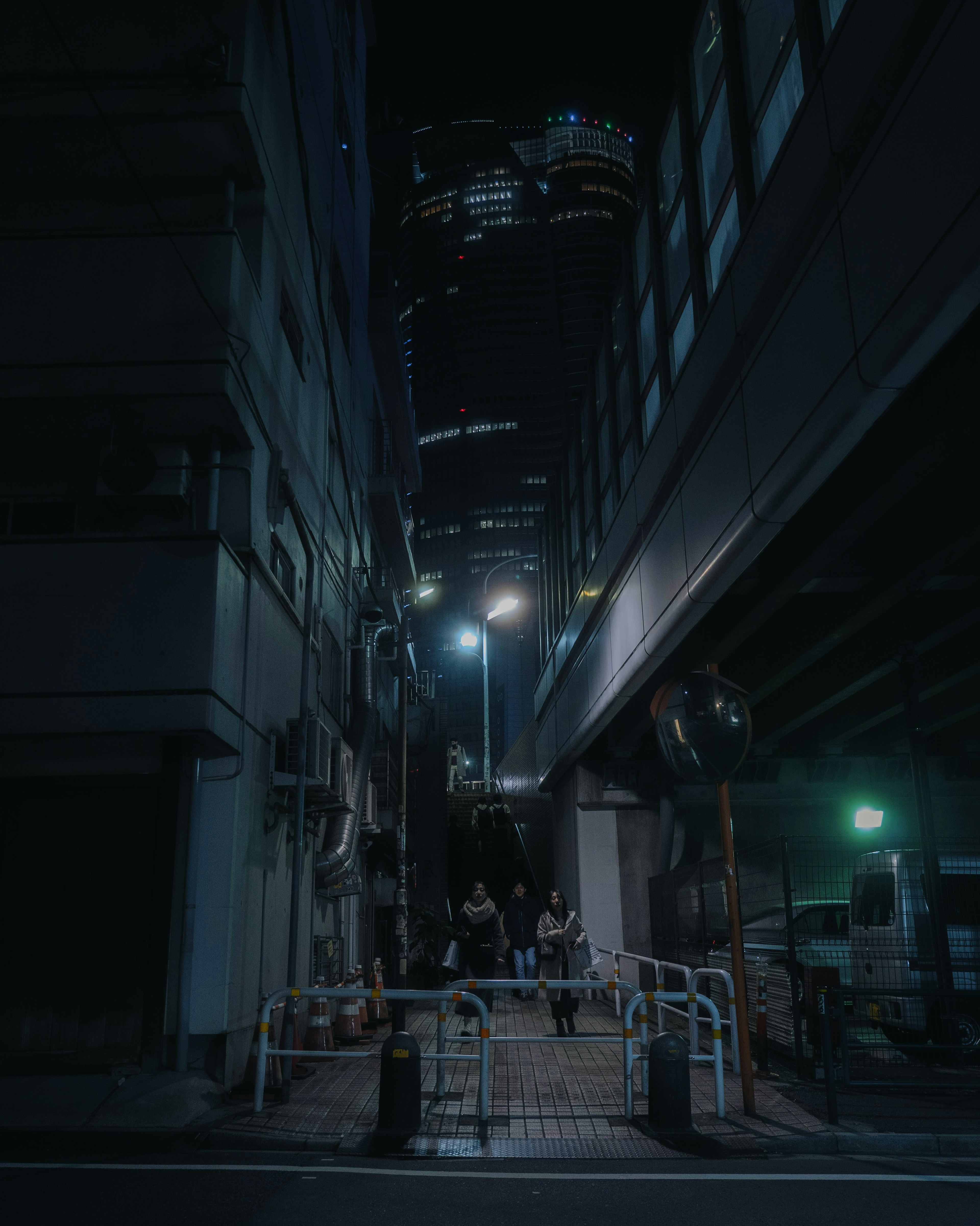 Escena urbana nocturna con edificios altos y farolas en un callejón estrecho