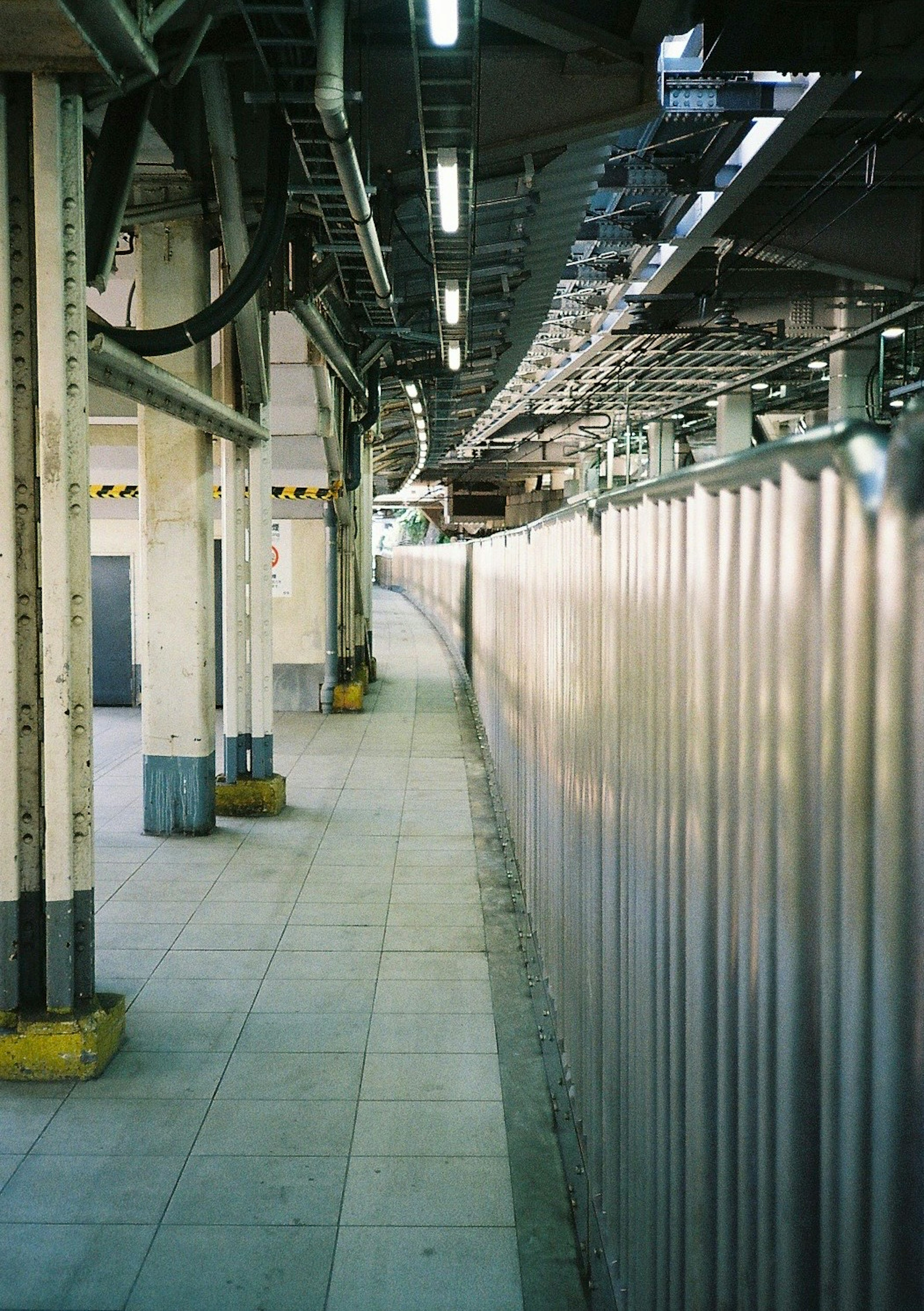 Vista di un marciapiede con elementi strutturali e una recinzione in metallo in una stazione