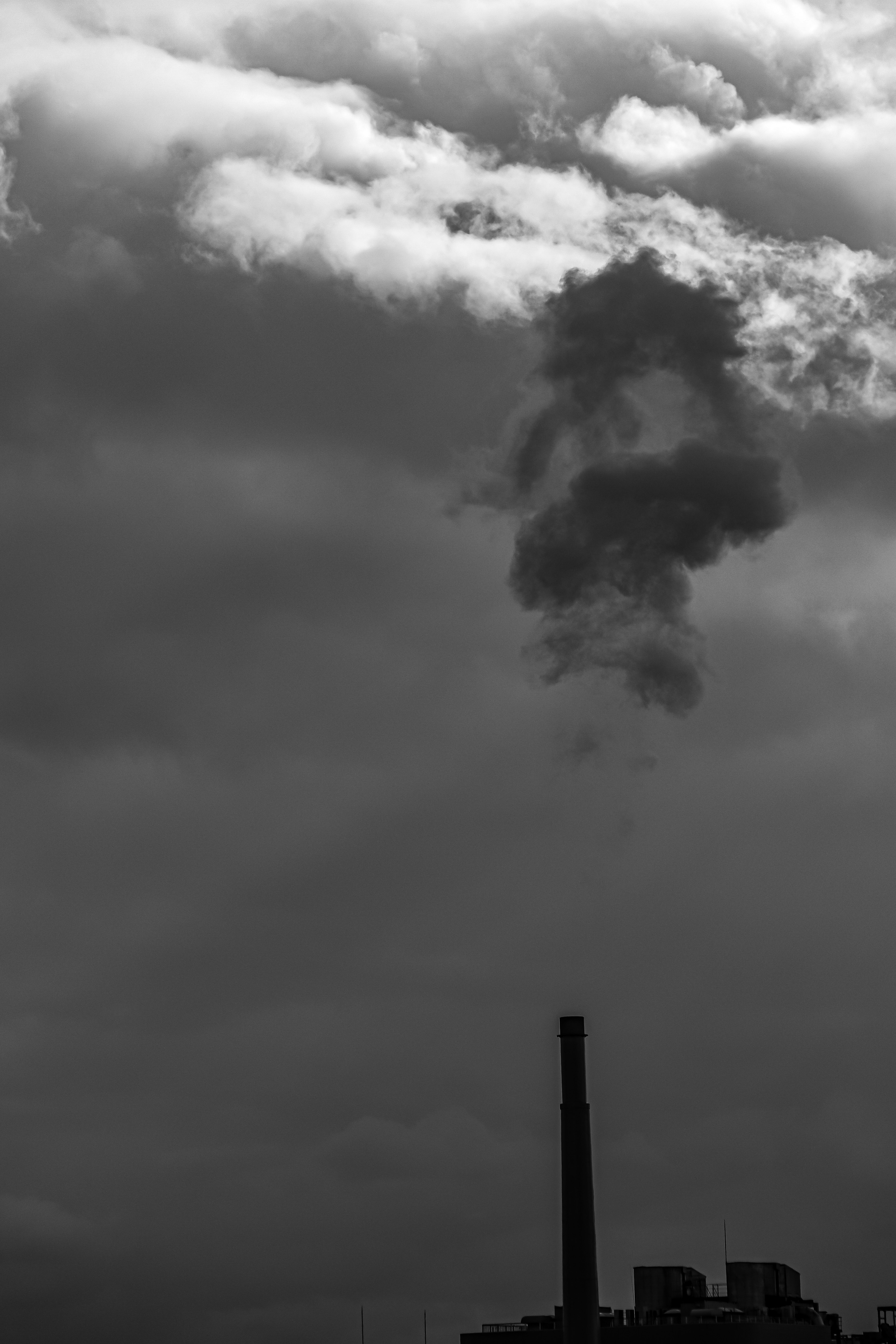 Chimenea de fábrica emitiendo humo contra nubes oscuras