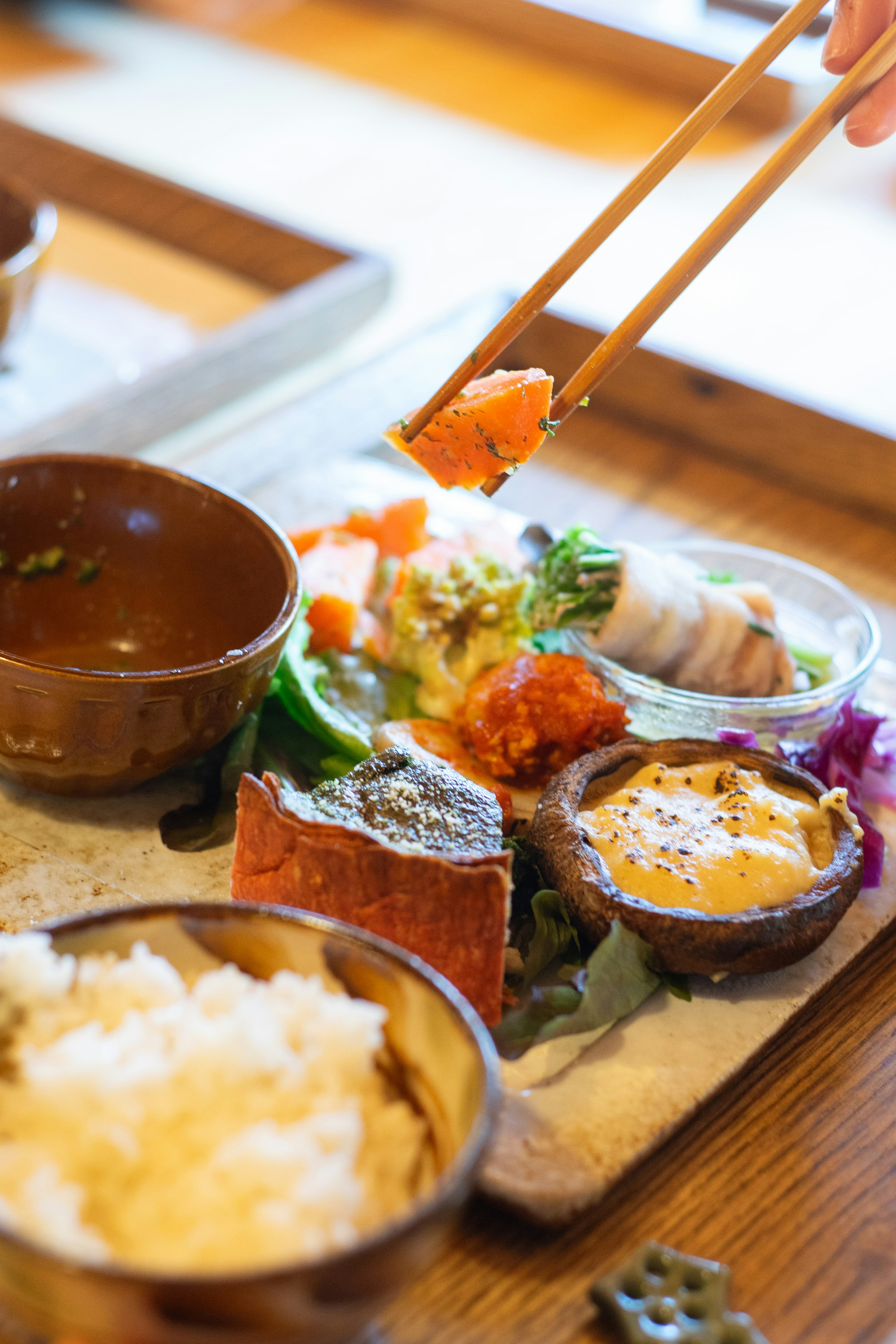 Una bandeja de sushi bellamente presentada con arroz y guarniciones