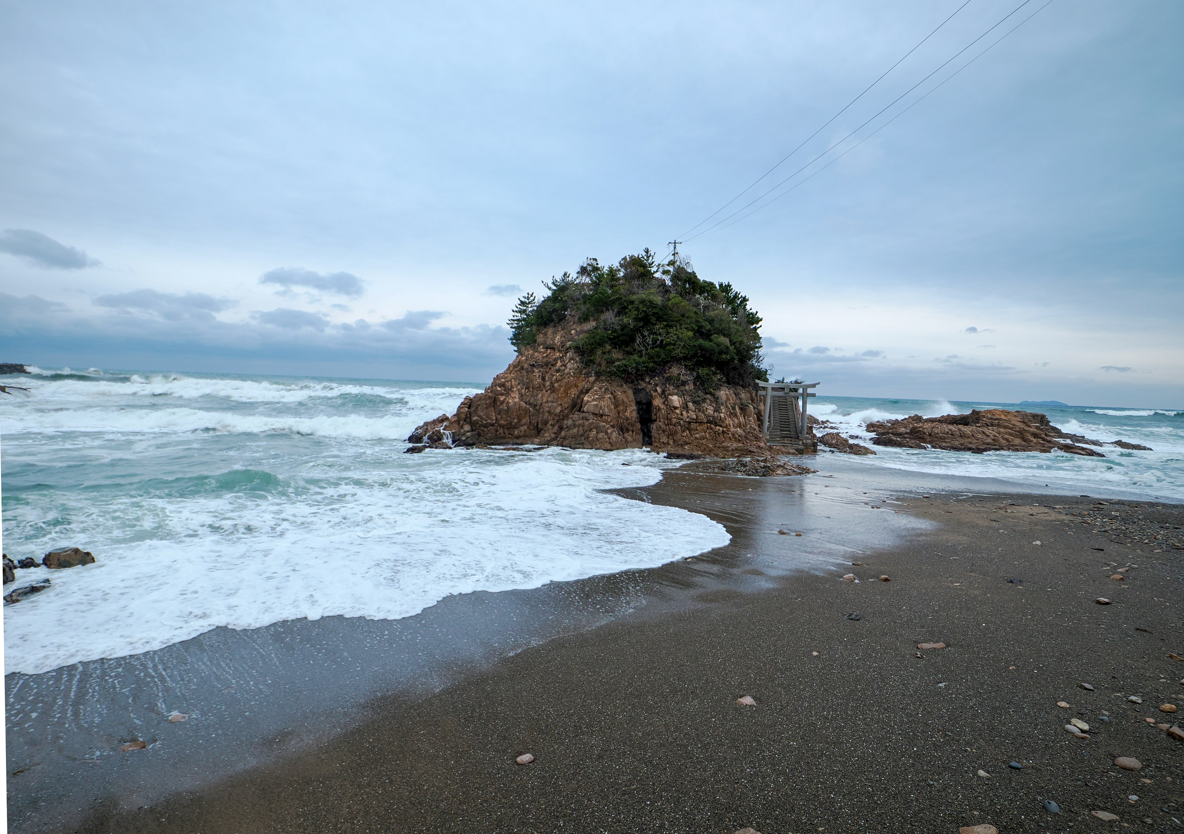 Vista costera con isla rocosa y olas rompiendo