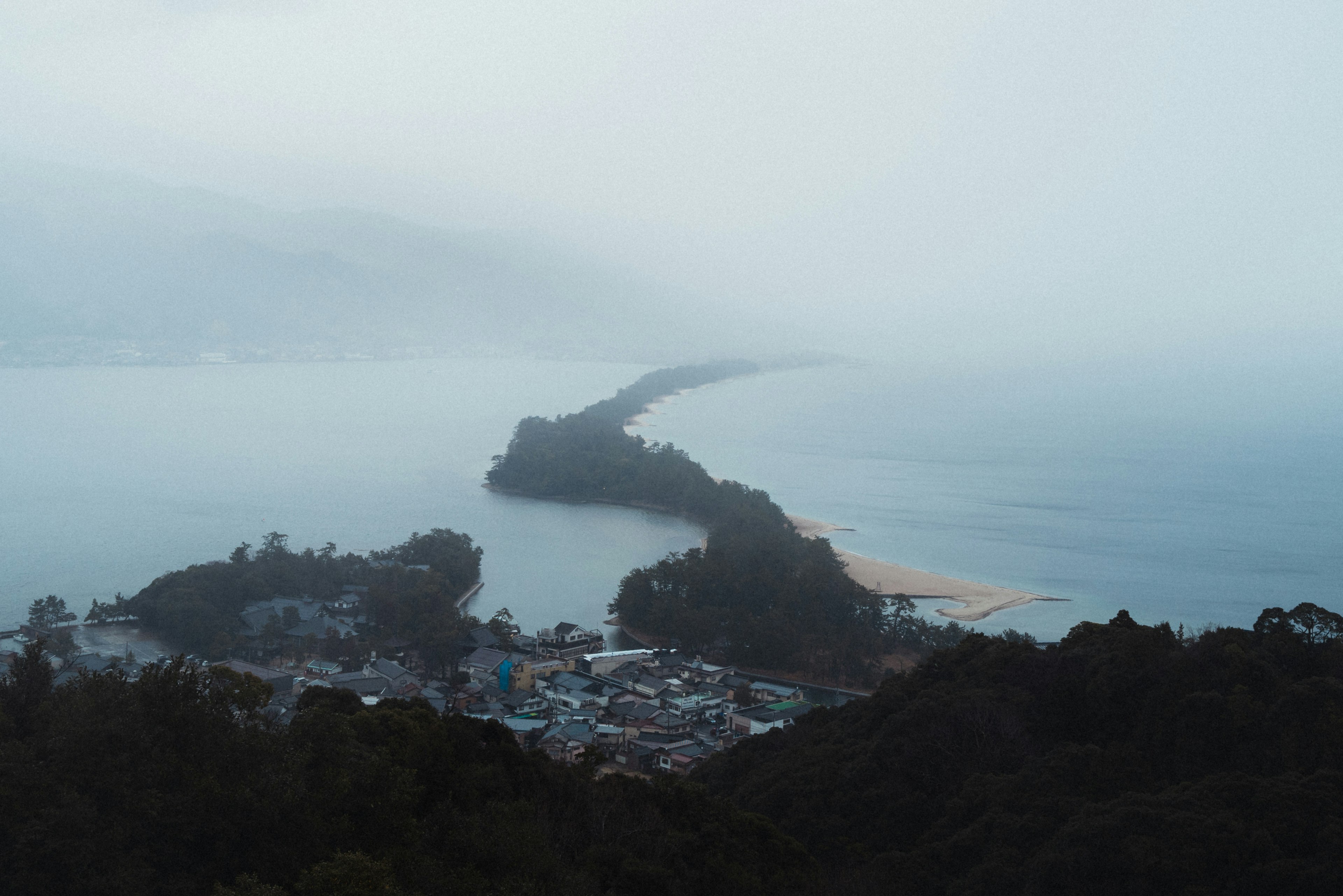 霧に包まれた海岸線と小さな町の風景