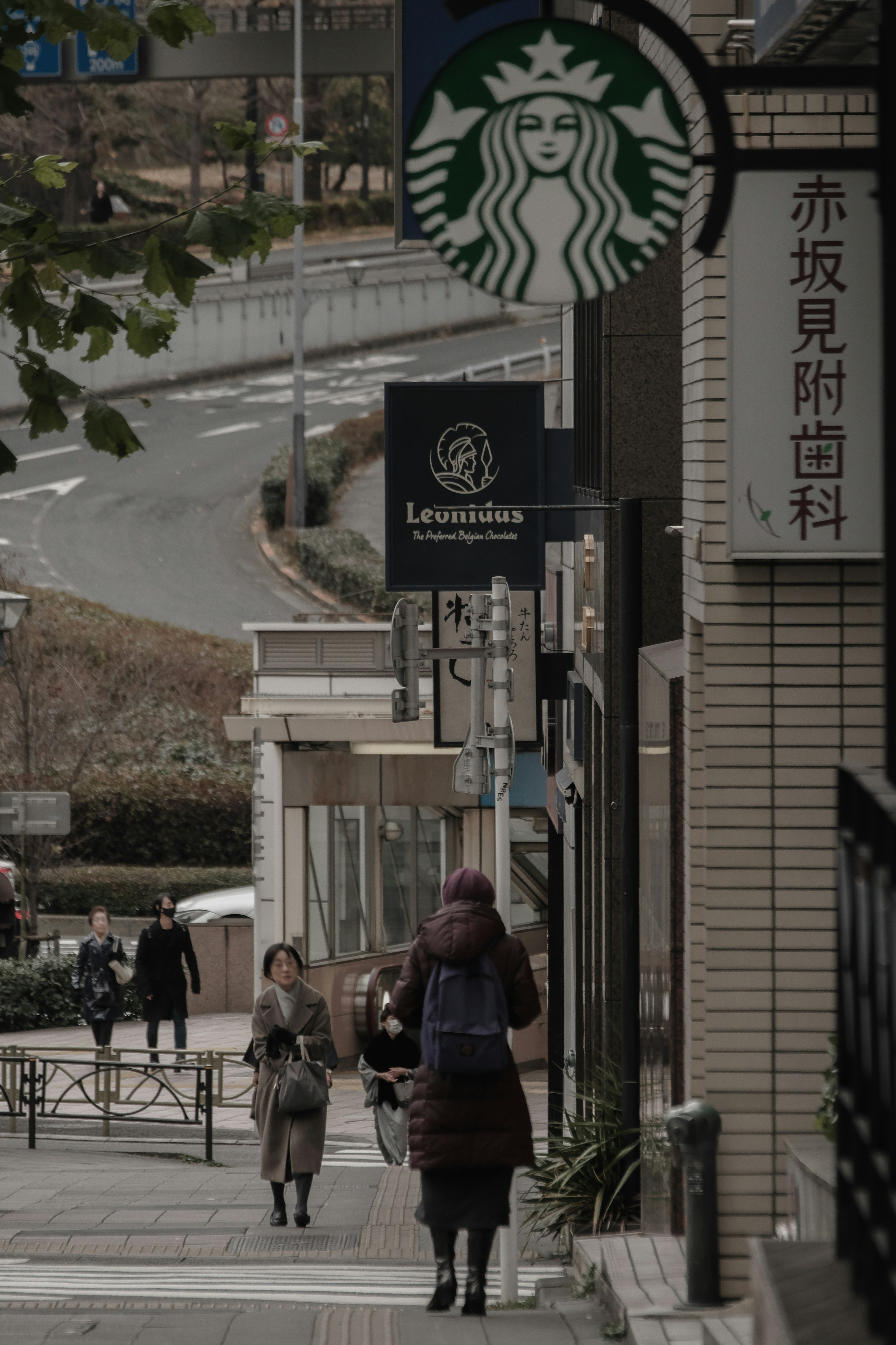 スターバックスの看板が見える街角の風景 歩道を歩く人々と建物