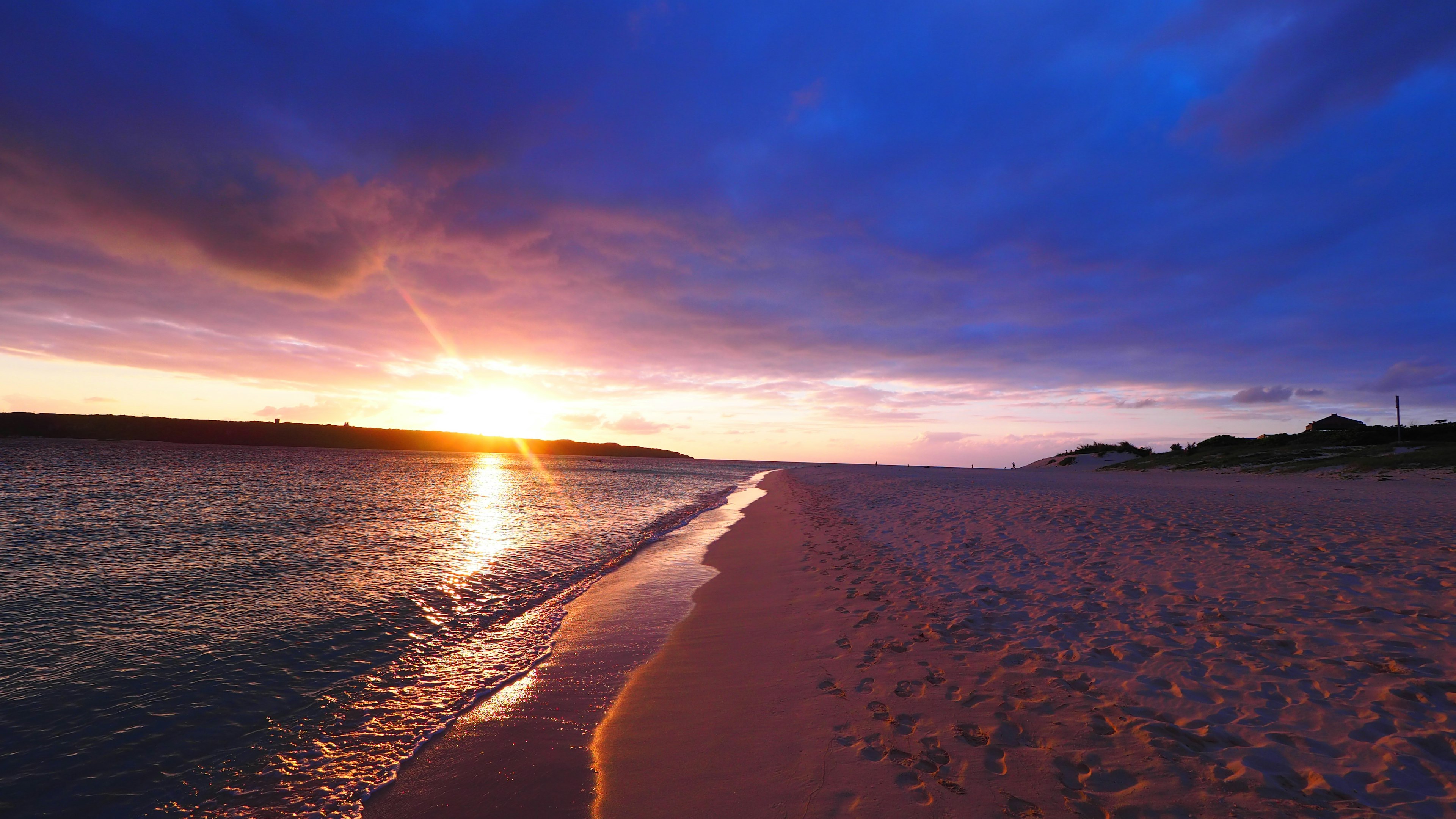 Beach landscape with sunset over water blue sky and purple clouds