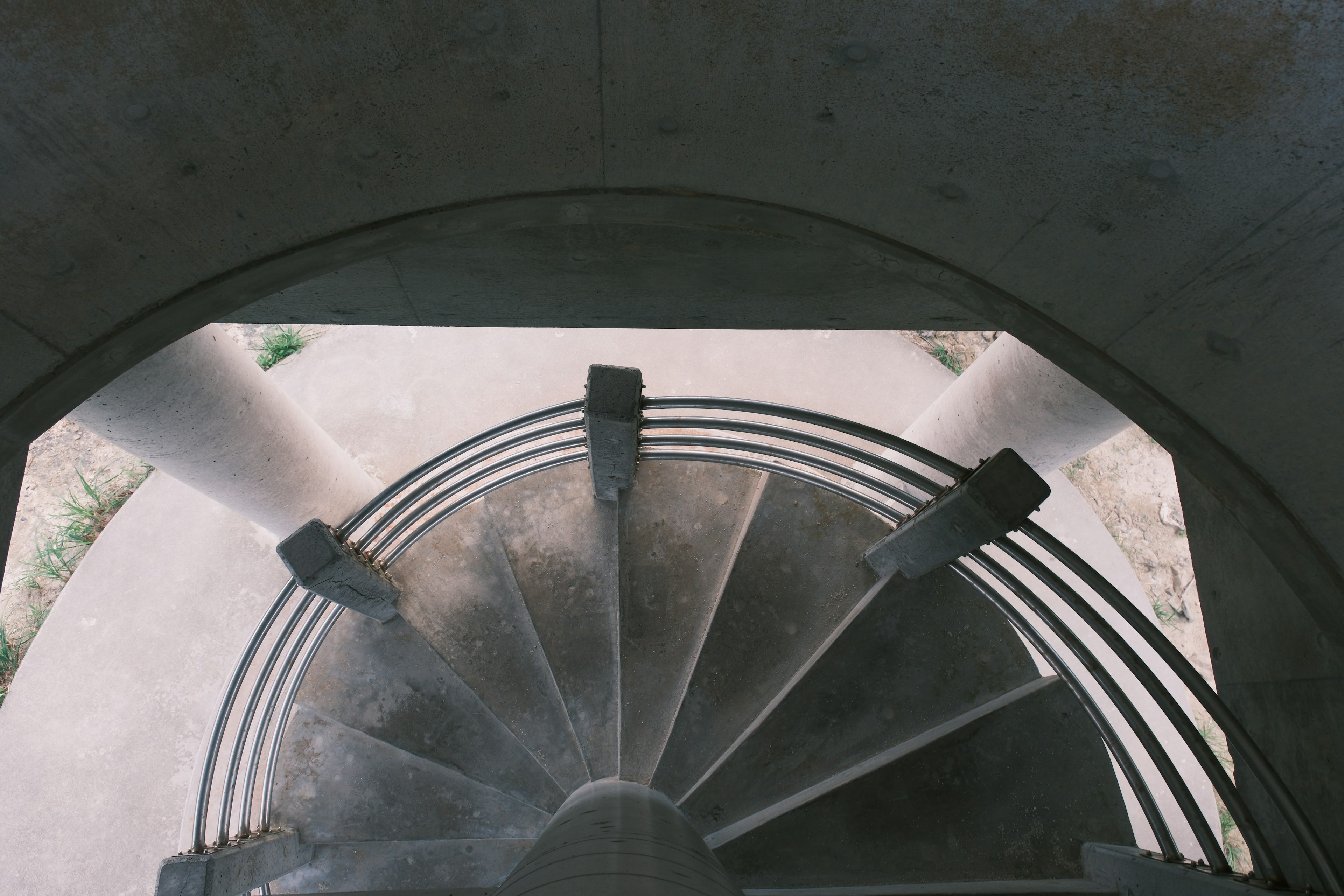 Blick von oben auf eine Wendeltreppe mit Betonstruktur und Säulen