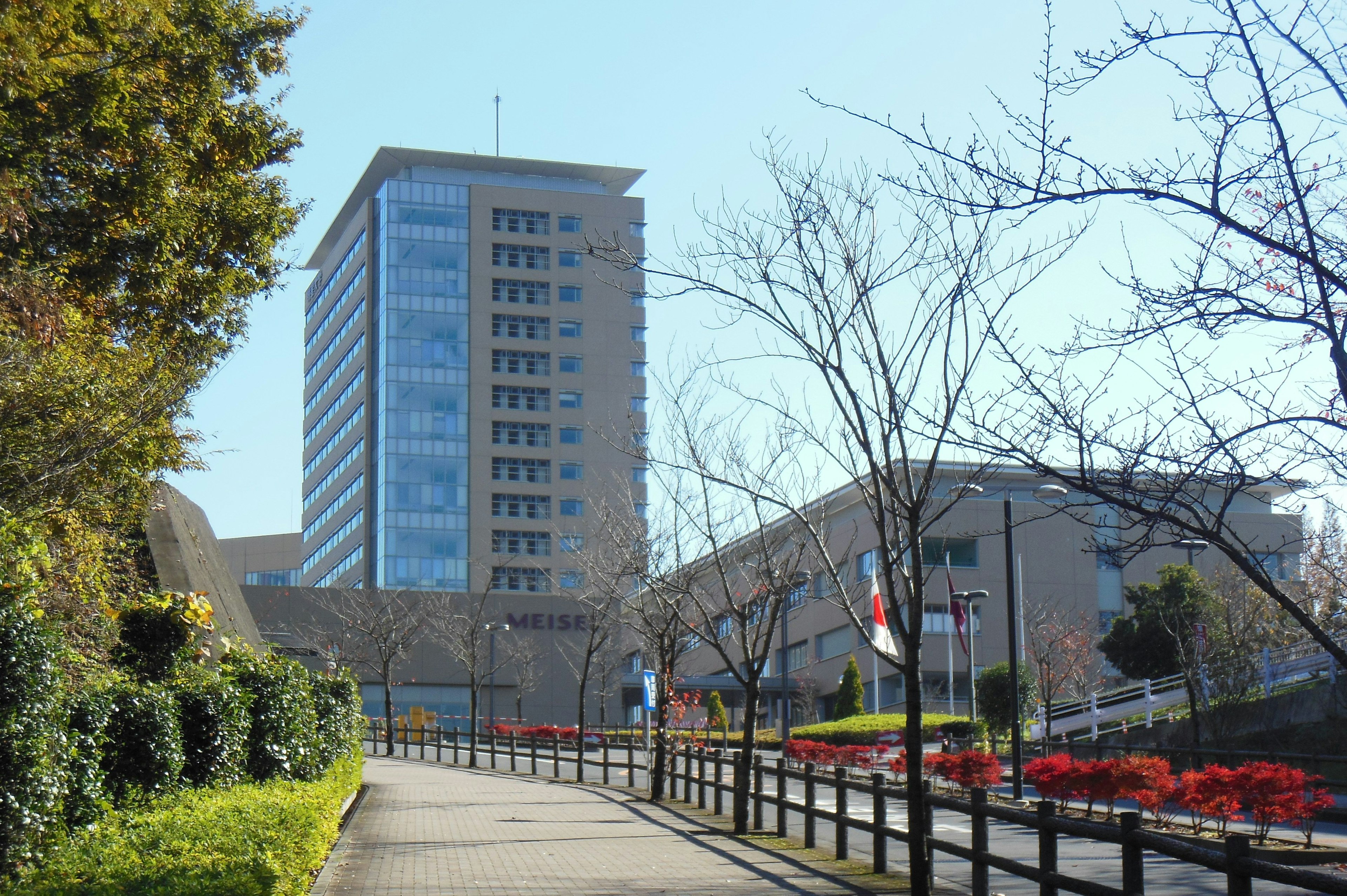 Un alto edificio sotto un cielo blu con alberi lungo un sentiero