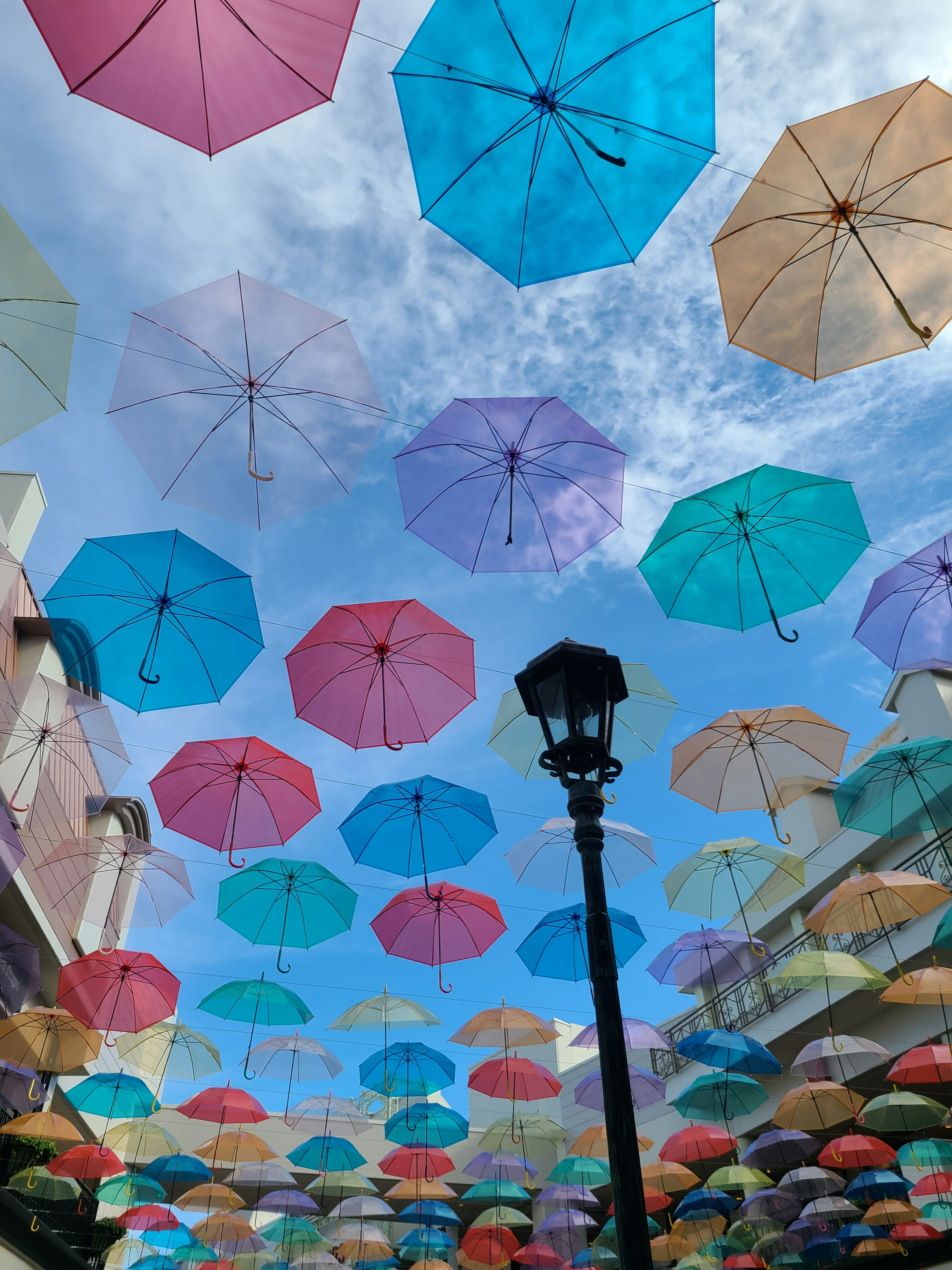 Colorful umbrellas suspended in the sky with a lamppost