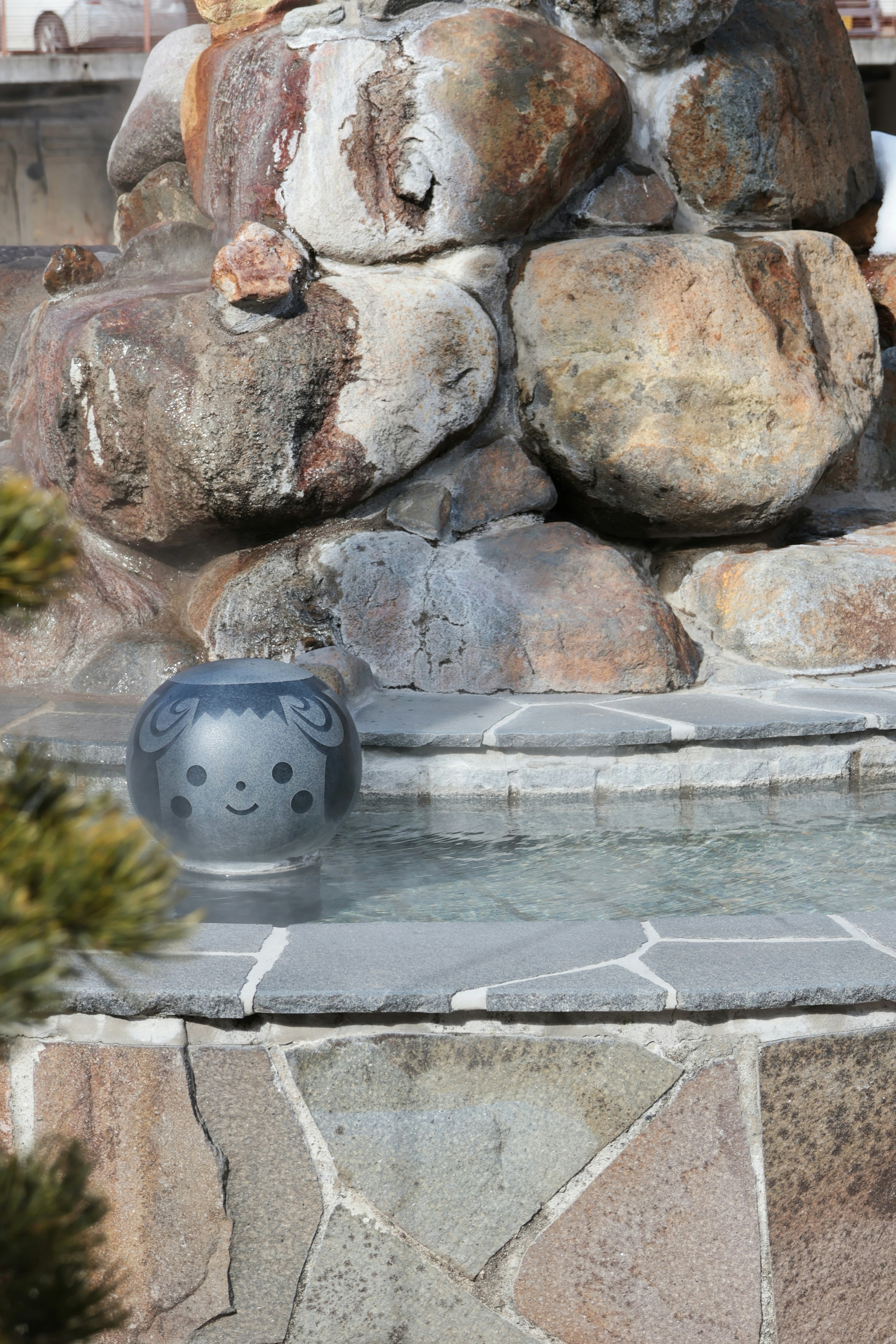 Fontaine décorative avec un mur en pierre et un objet en céramique bleue dans l'eau