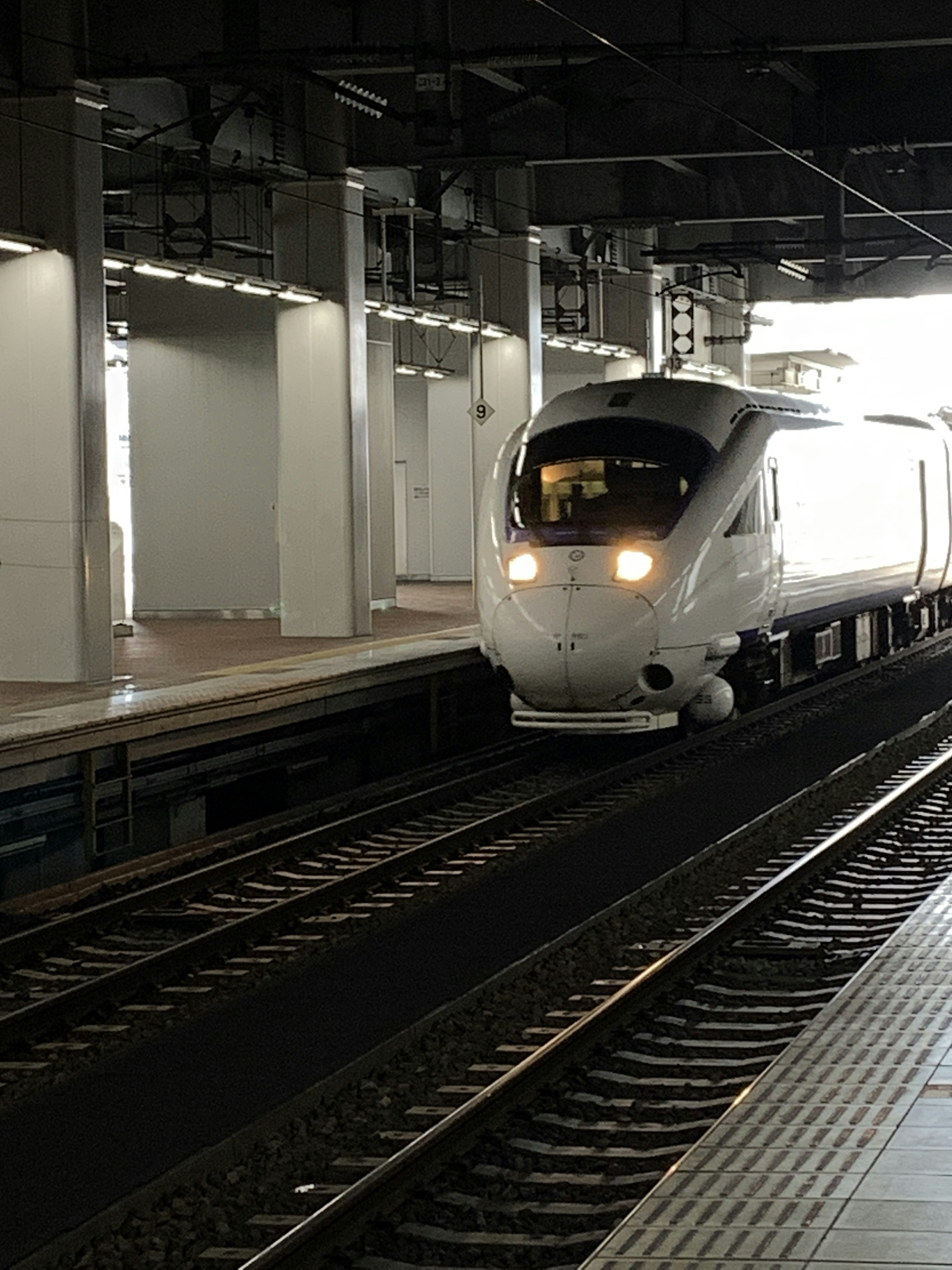 A white Shinkansen train arriving at a station