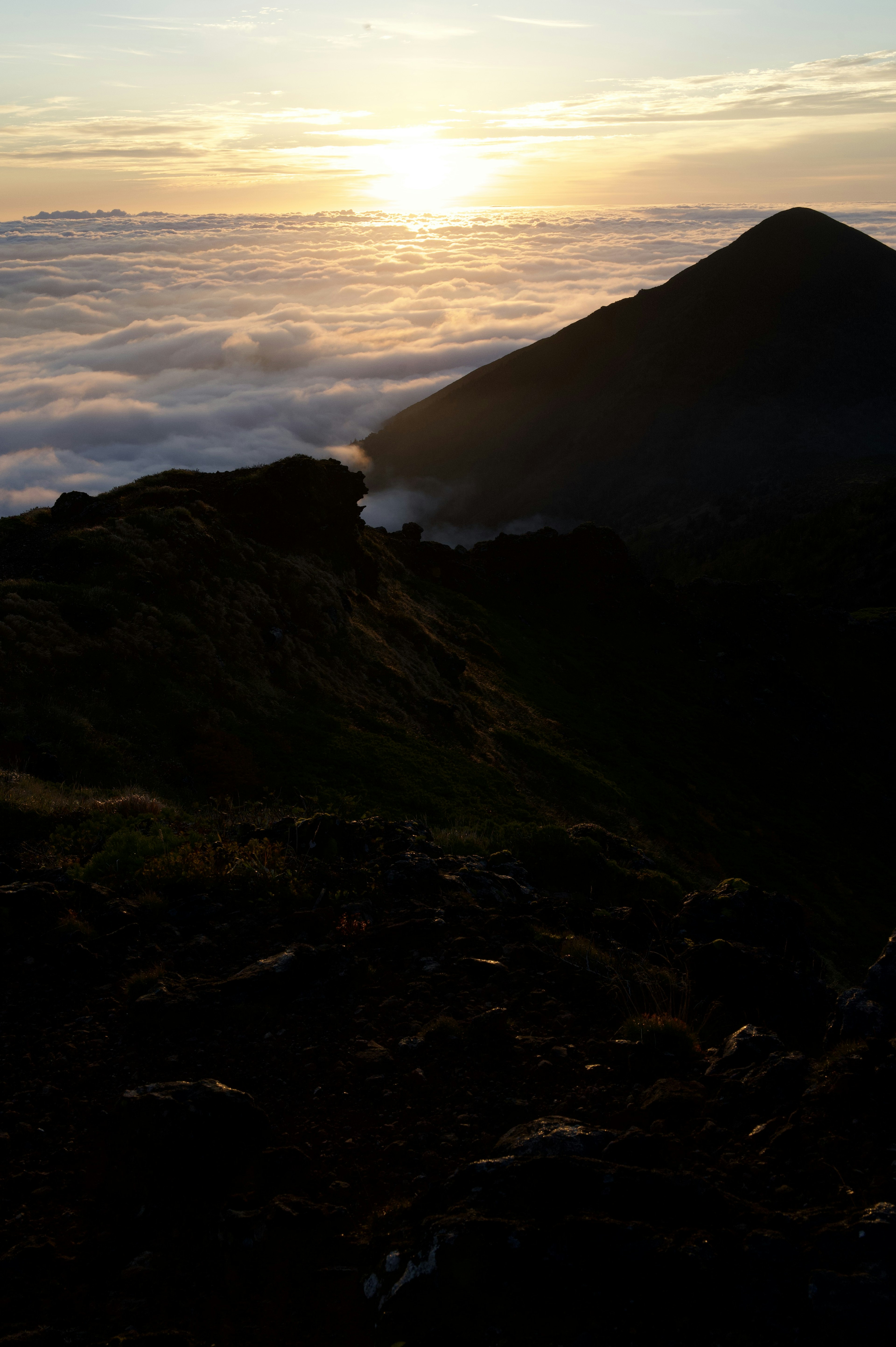 Matahari terbit di atas lautan awan dengan siluet gunung