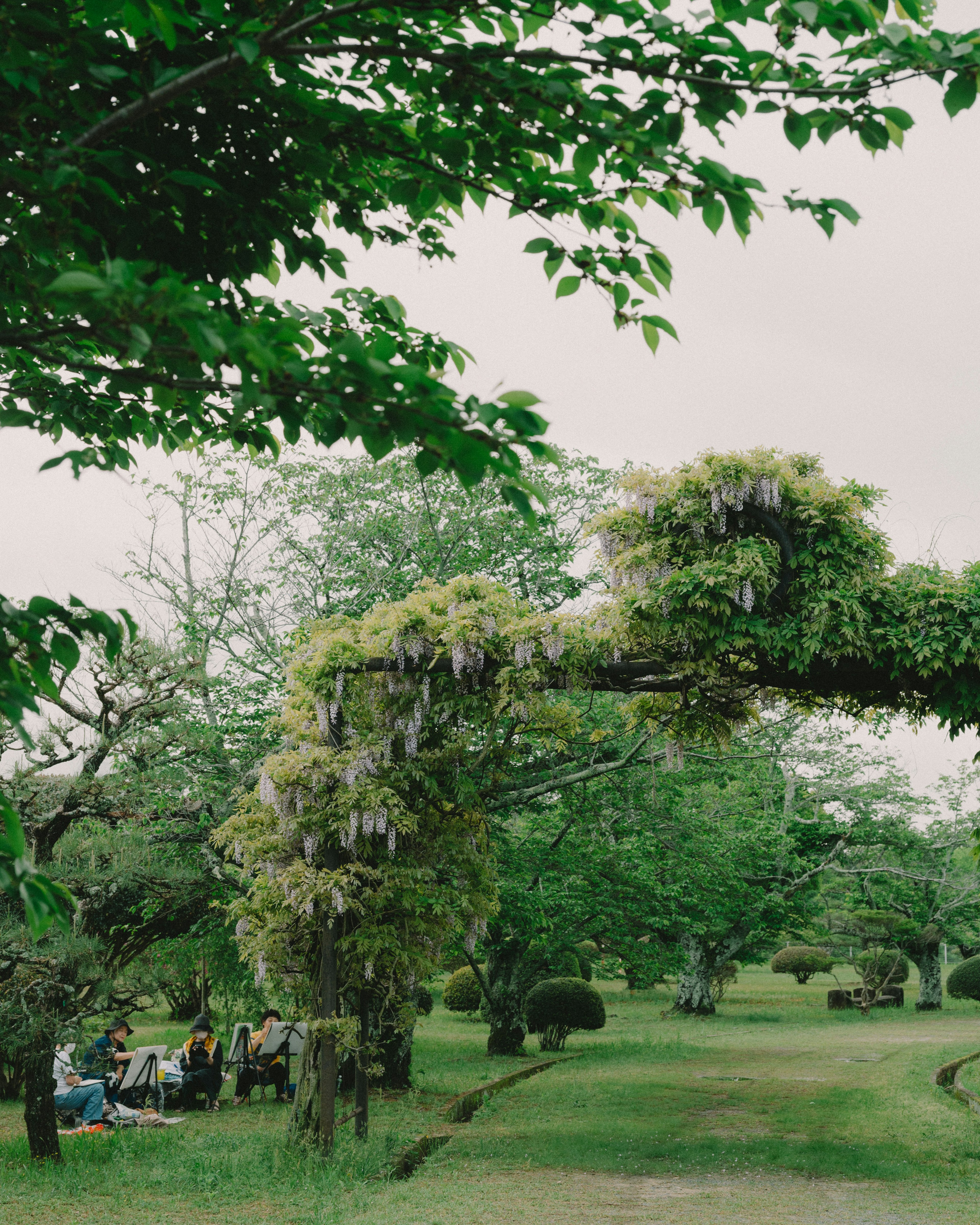 People gathered under a green arch adorned with flowers and foliage