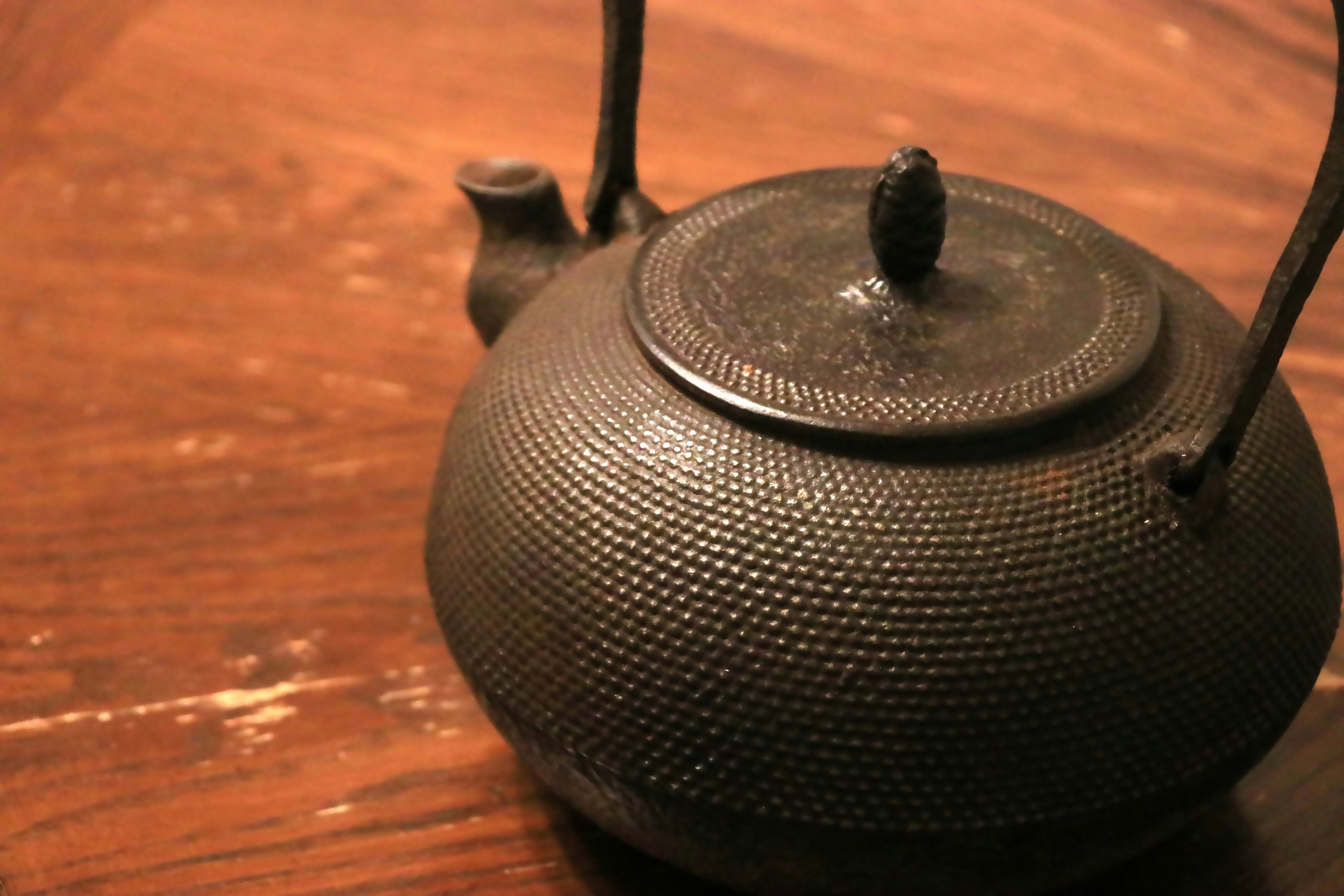 A black iron teapot on a wooden table